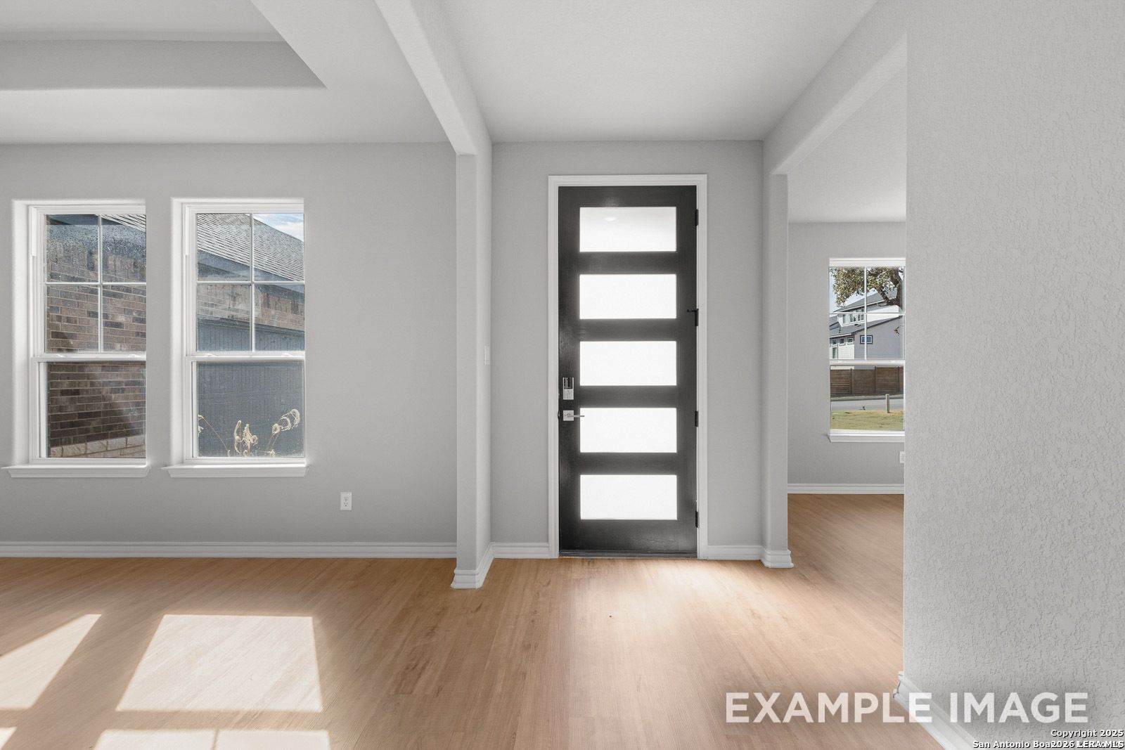 Modern entryway with light wood flooring and contemporary glass-paneled front door in Davidson Homes Oxford F floor plan.