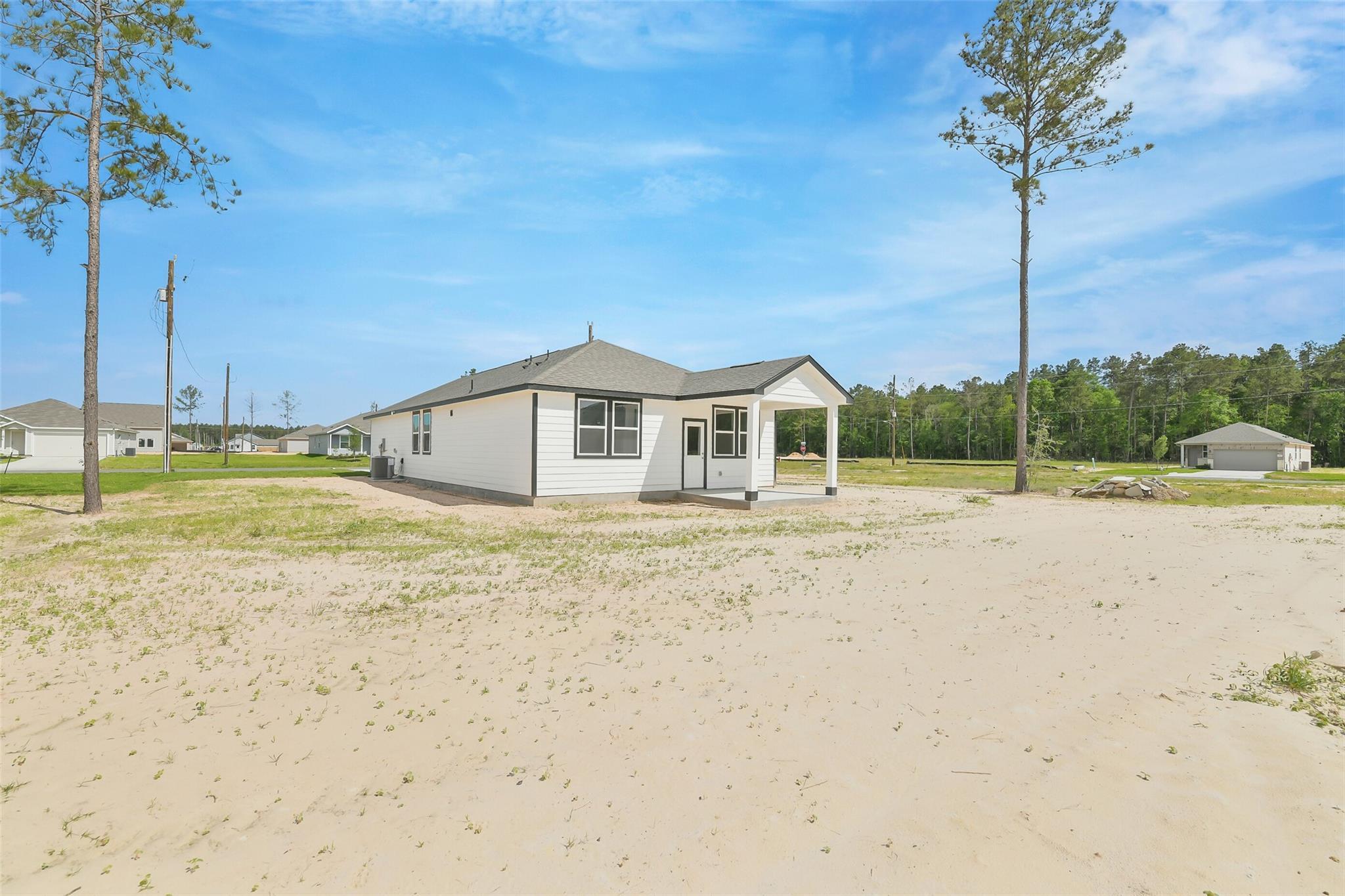 White single-story 3-bedroom home with covered porch and sandy yard in Spring Branch Crossing, Conroe, Texas by Davidson Homes The Frio G