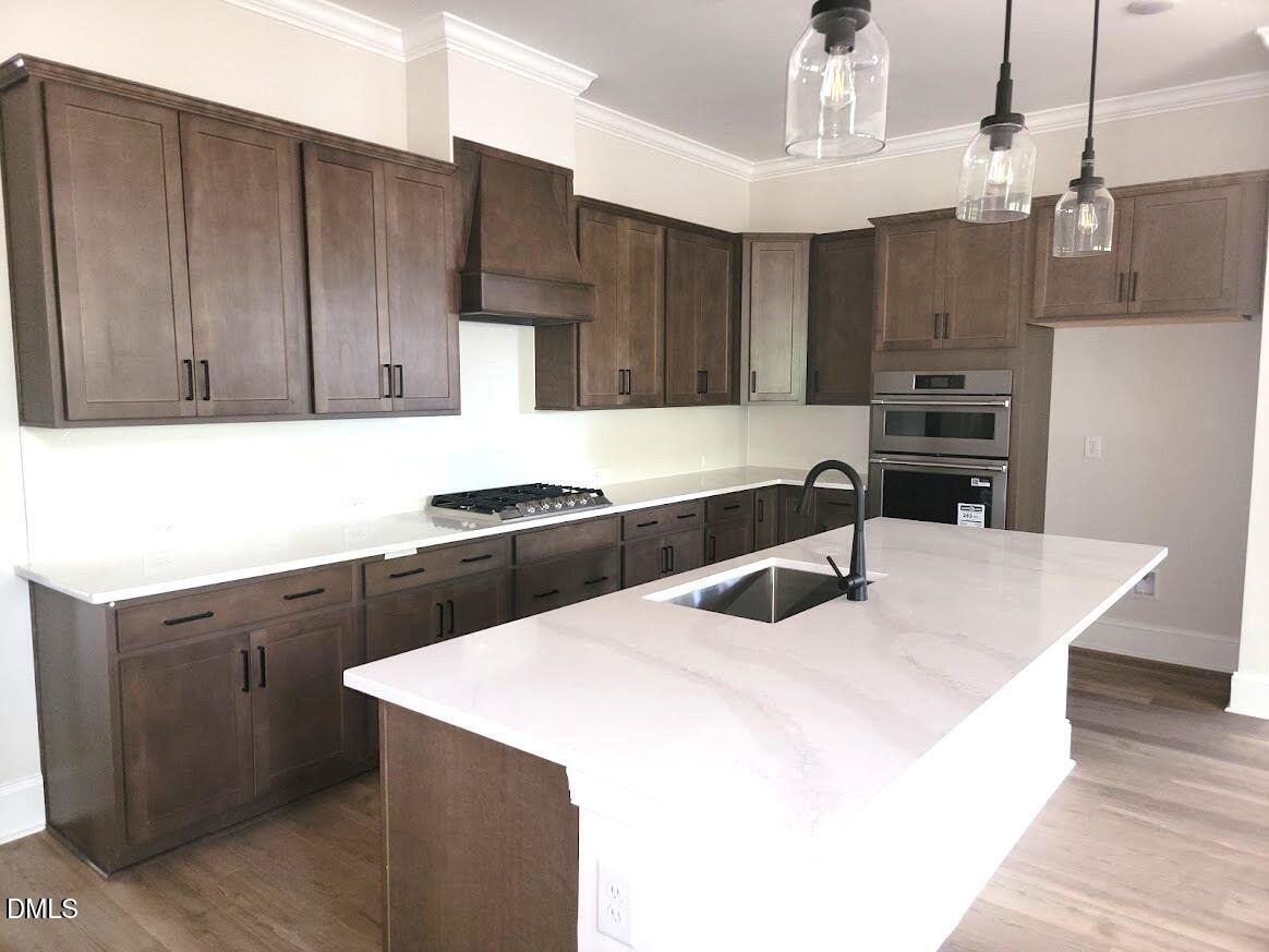 Kitchen island with white quartz countertops, dark wood cabinets, and pendant lighting in Davidson Homes Magnolia II B, Wake Forest NC
