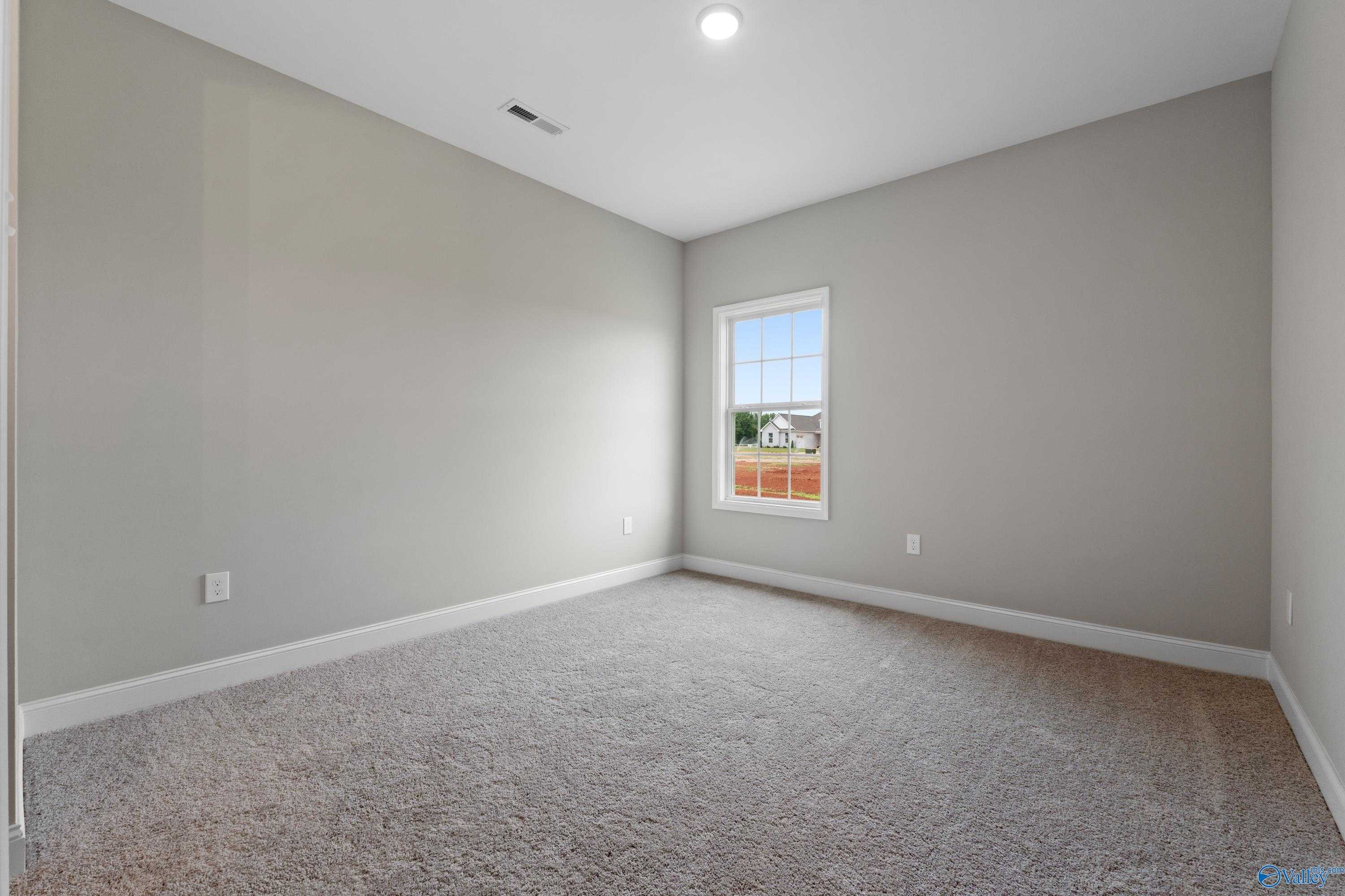 Bright secondary bedroom with neutral gray walls, plush beige carpet, and large window in Davidson Homes The Finleigh, Meridianville, Alabama