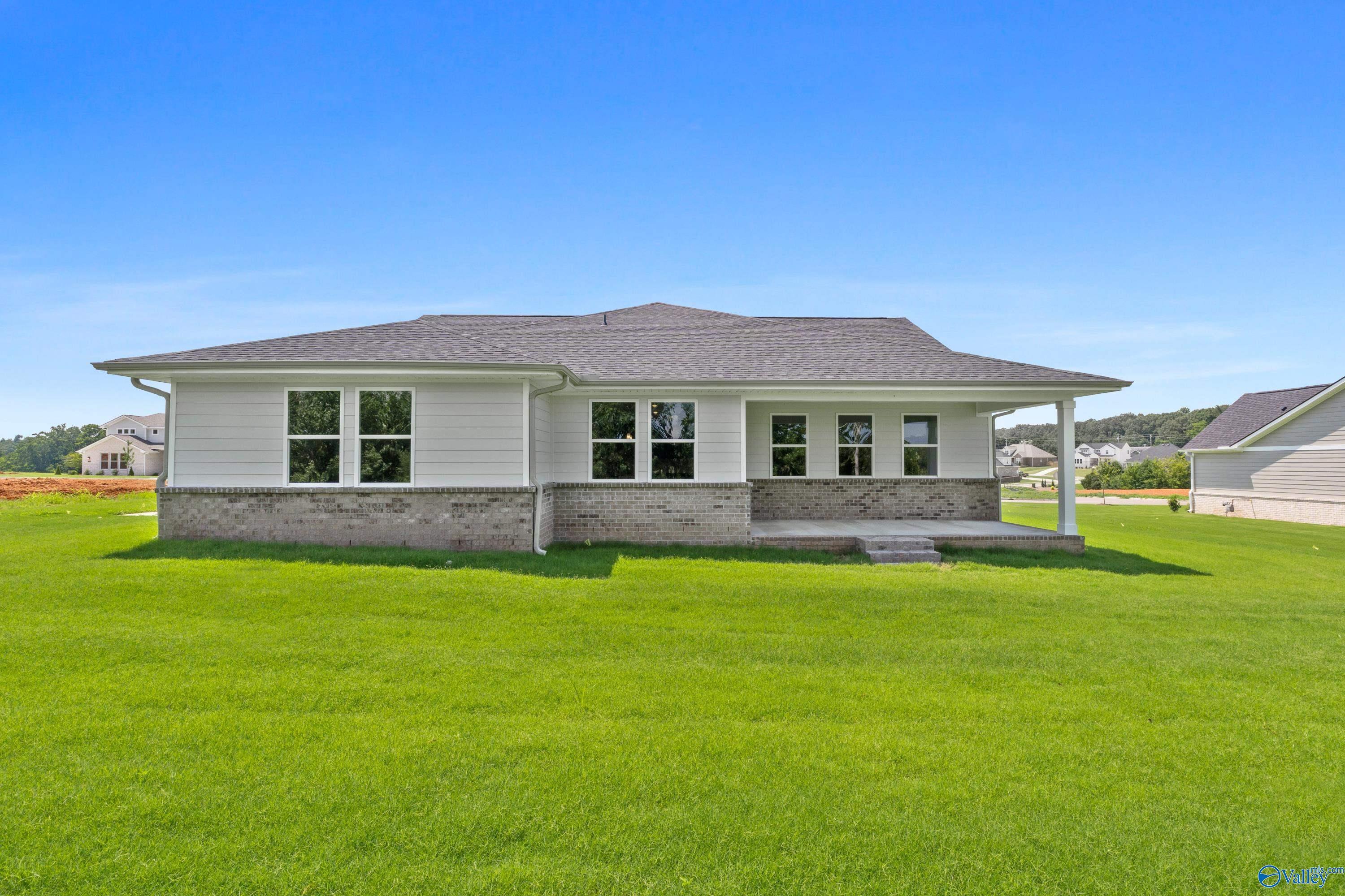 Single-story white ranch home with dark shingle roof, large windows, brick base, and covered porch on lush green lawn in Riverton Preserve, Huntsville, Alabama