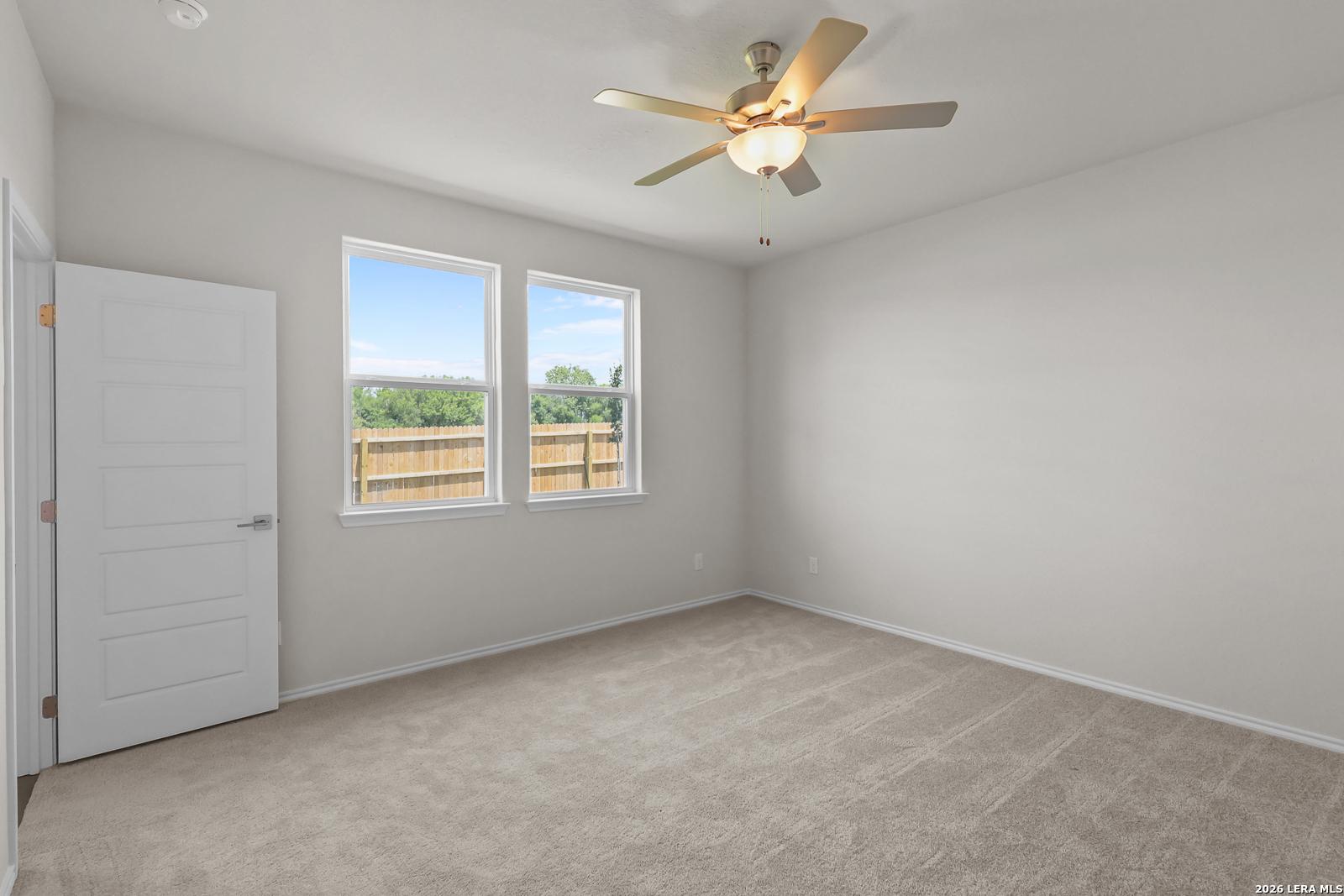Bright, carpeted bedroom with ceiling fan in The San Marcos F floor plan at Rayburn Valley, San Antonio, Texas.