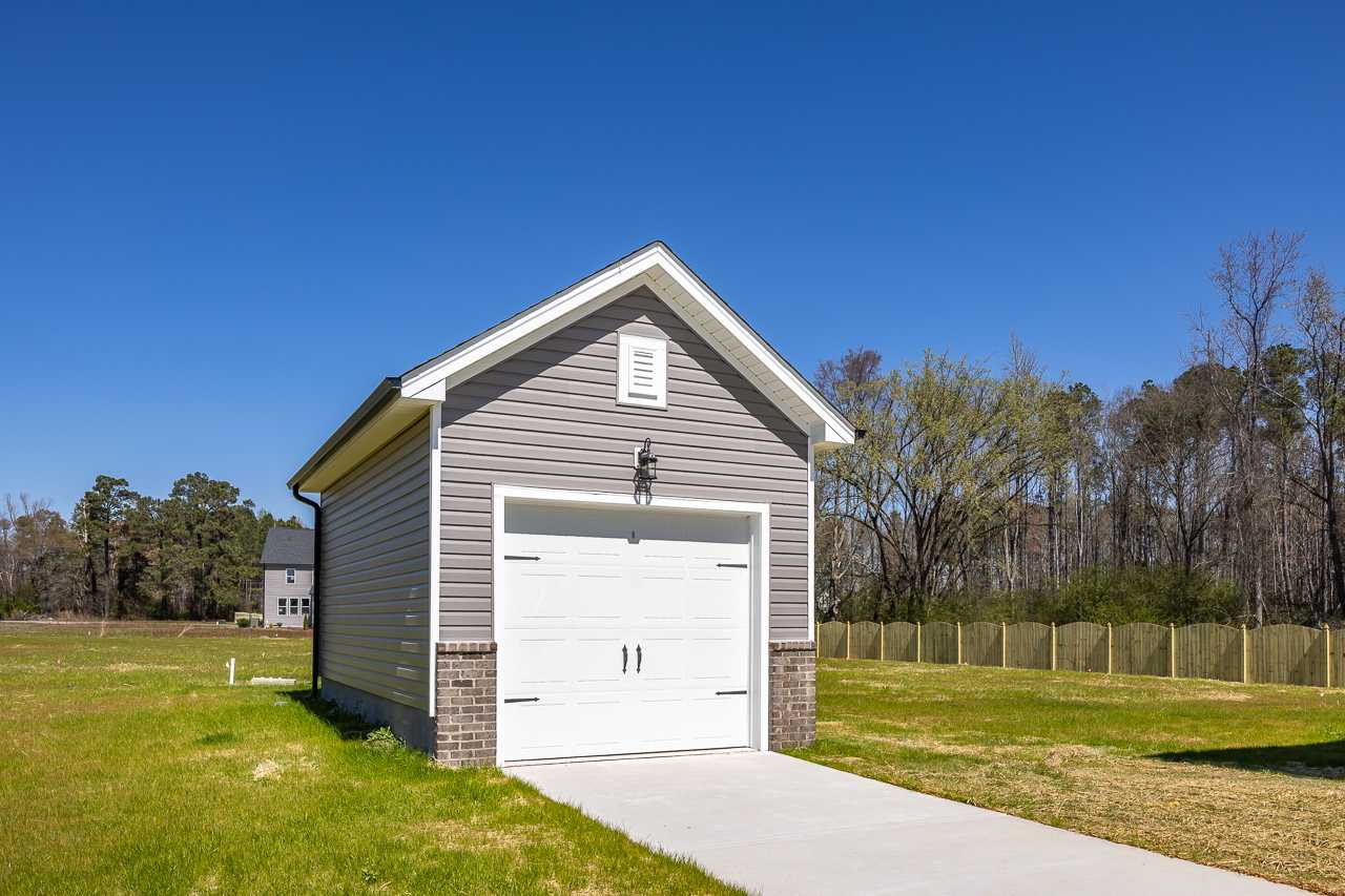 Detached gray siding garage with white door and brick accents at Wellers Knoll in Lillington NC