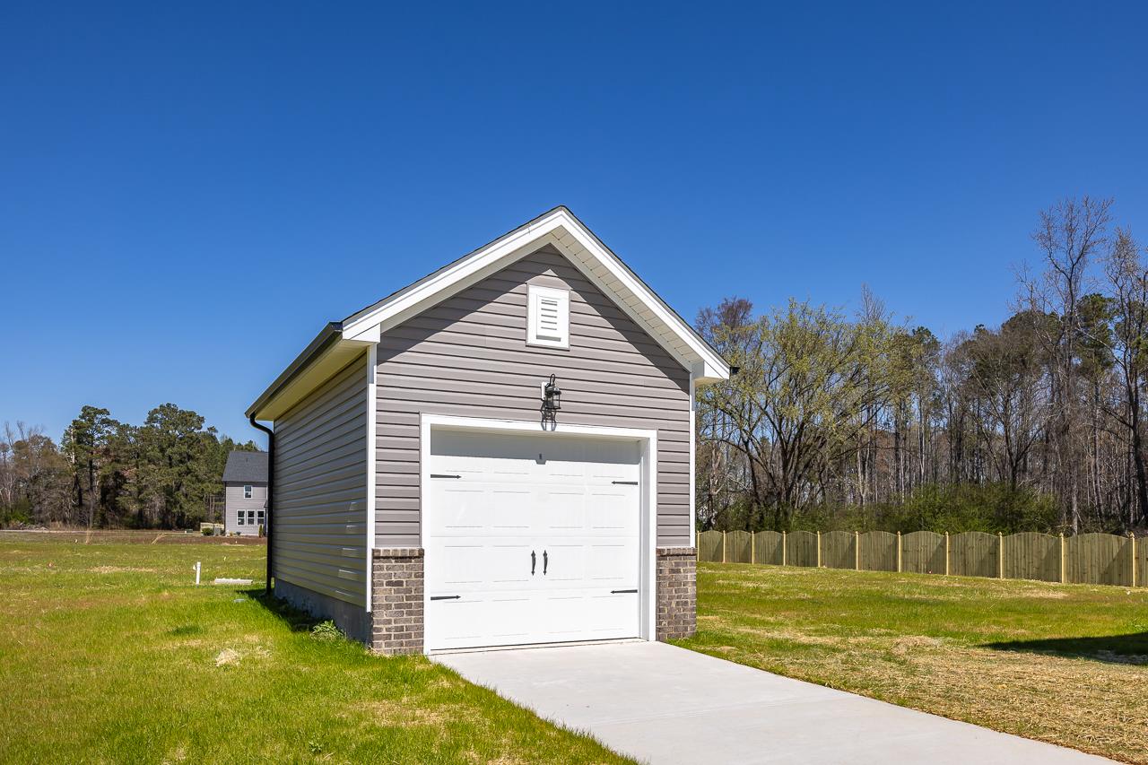 Detached gray siding garage with white door and brick accents at Wellers Knoll in Lillington NC