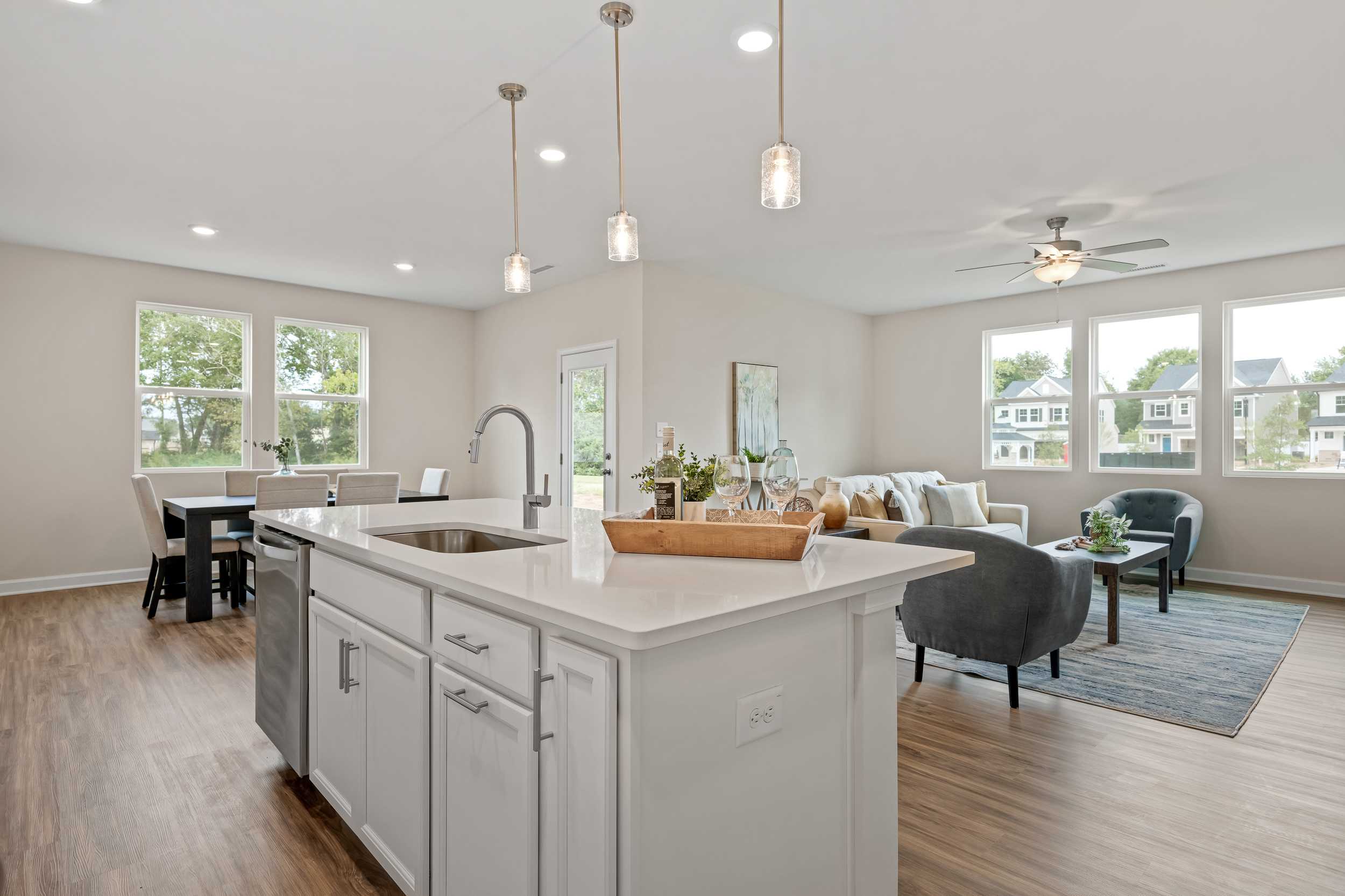 Open-concept kitchen and living room in Gregory Village Lillington NC home with white island sink, hardwood floors, pendant lights