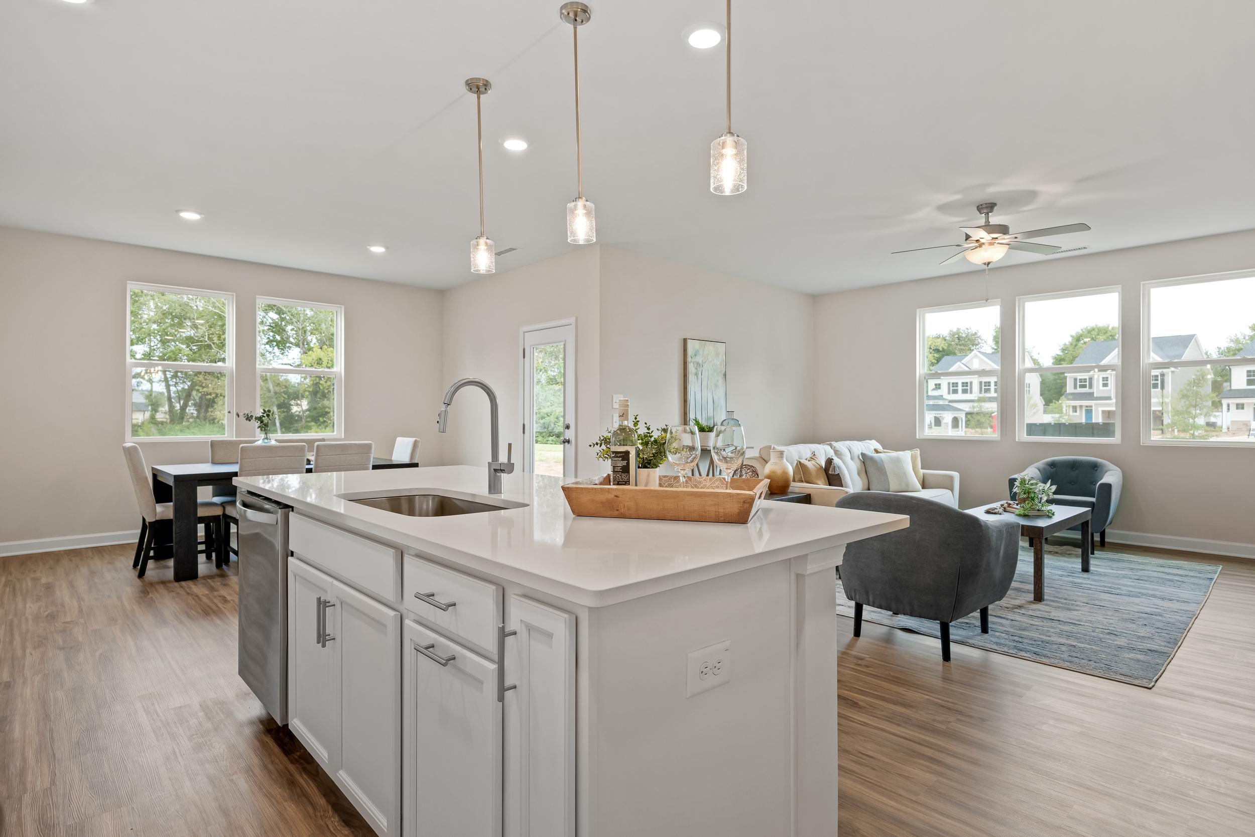 Open-concept kitchen and living room in Gregory Village Lillington NC home with white island sink, hardwood floors, pendant lights