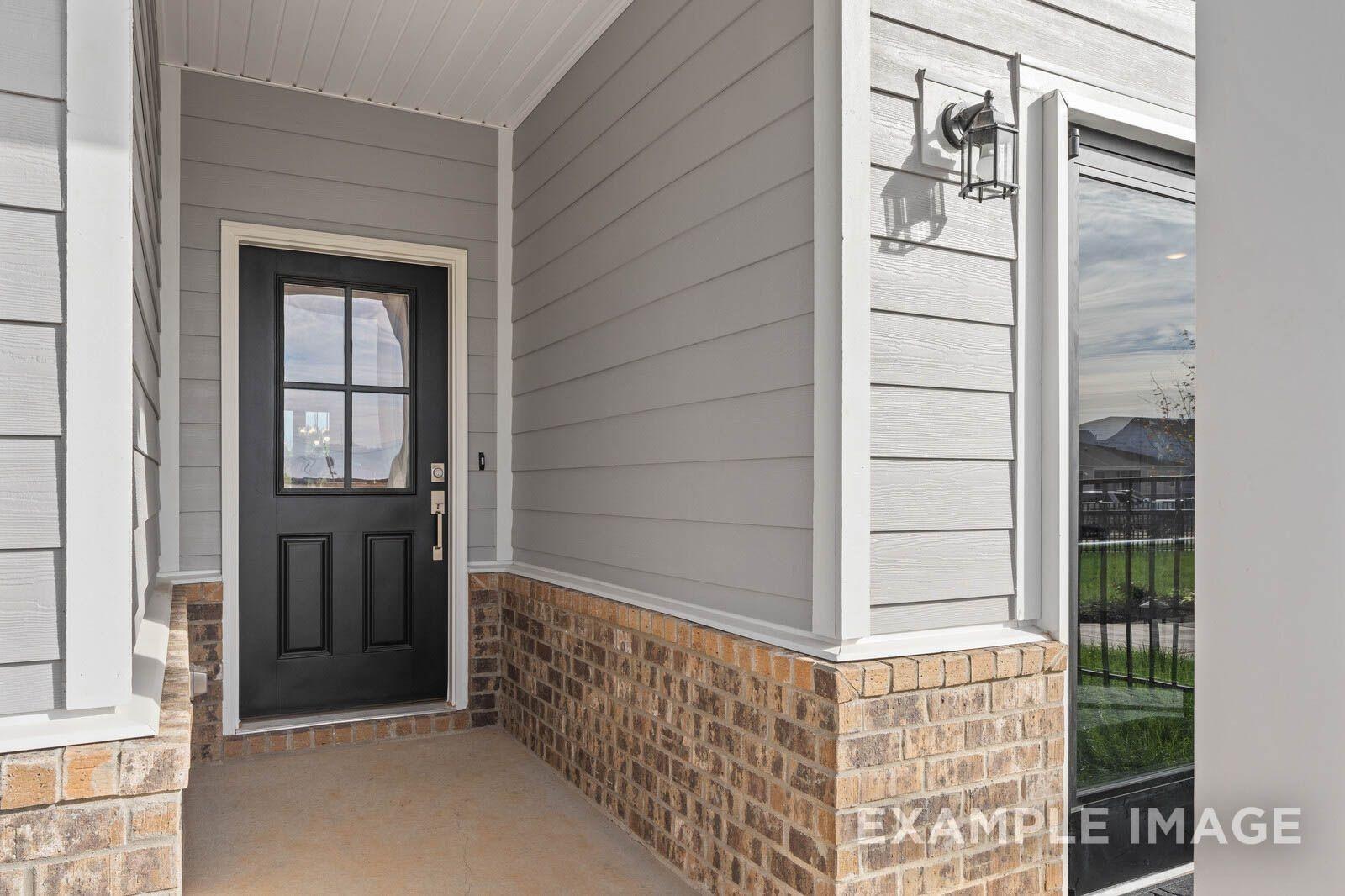 Stylish front entrance with black glass-paneled door, gray siding, brick accents, and covered porch in Davidson Homes Franklin B, Sage Farms, White House, TN