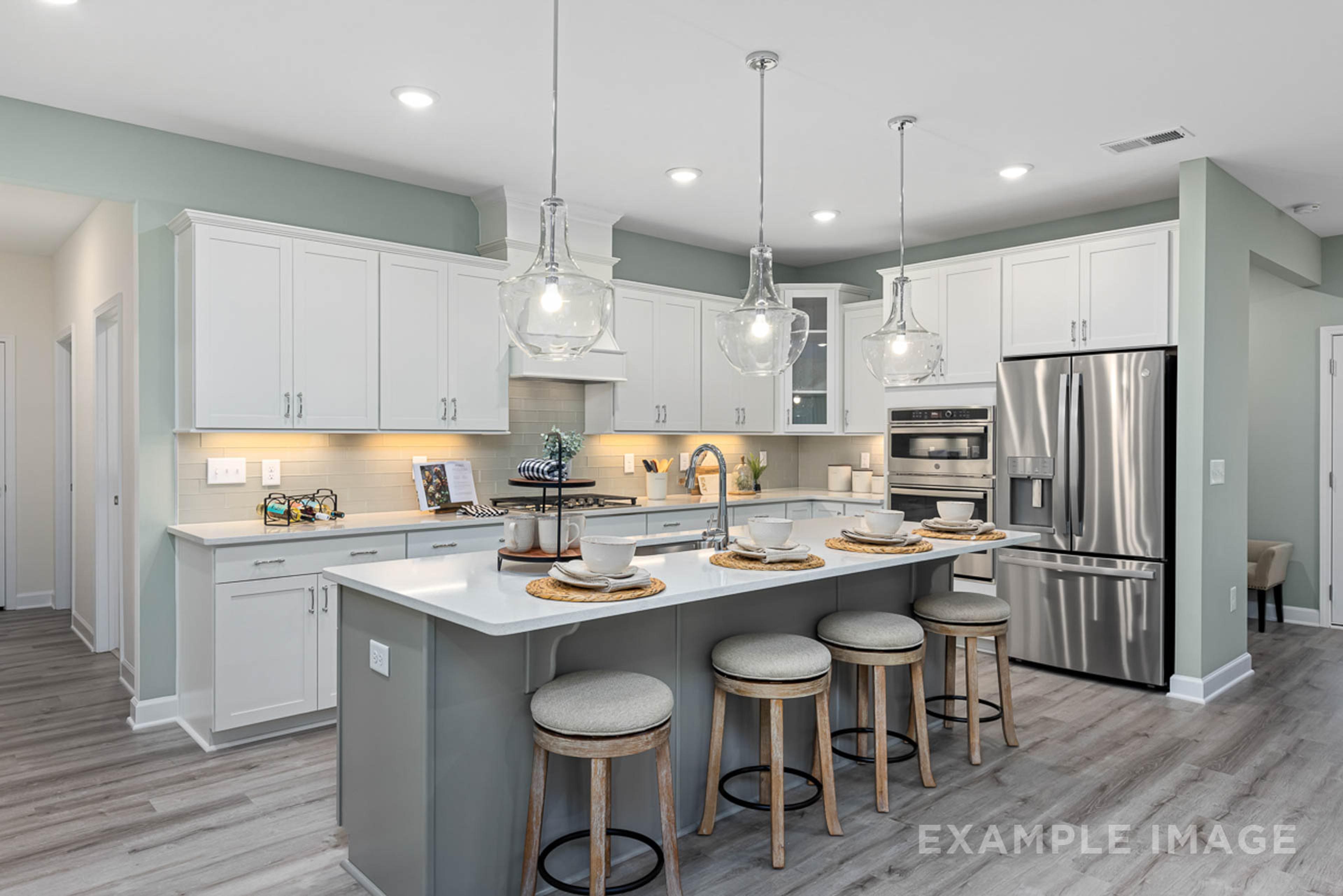 Modern open-concept kitchen in Windgate, Mooresville NC with white shaker cabinets, gray island, bar stools, stainless steel appliances, and hardwood floors