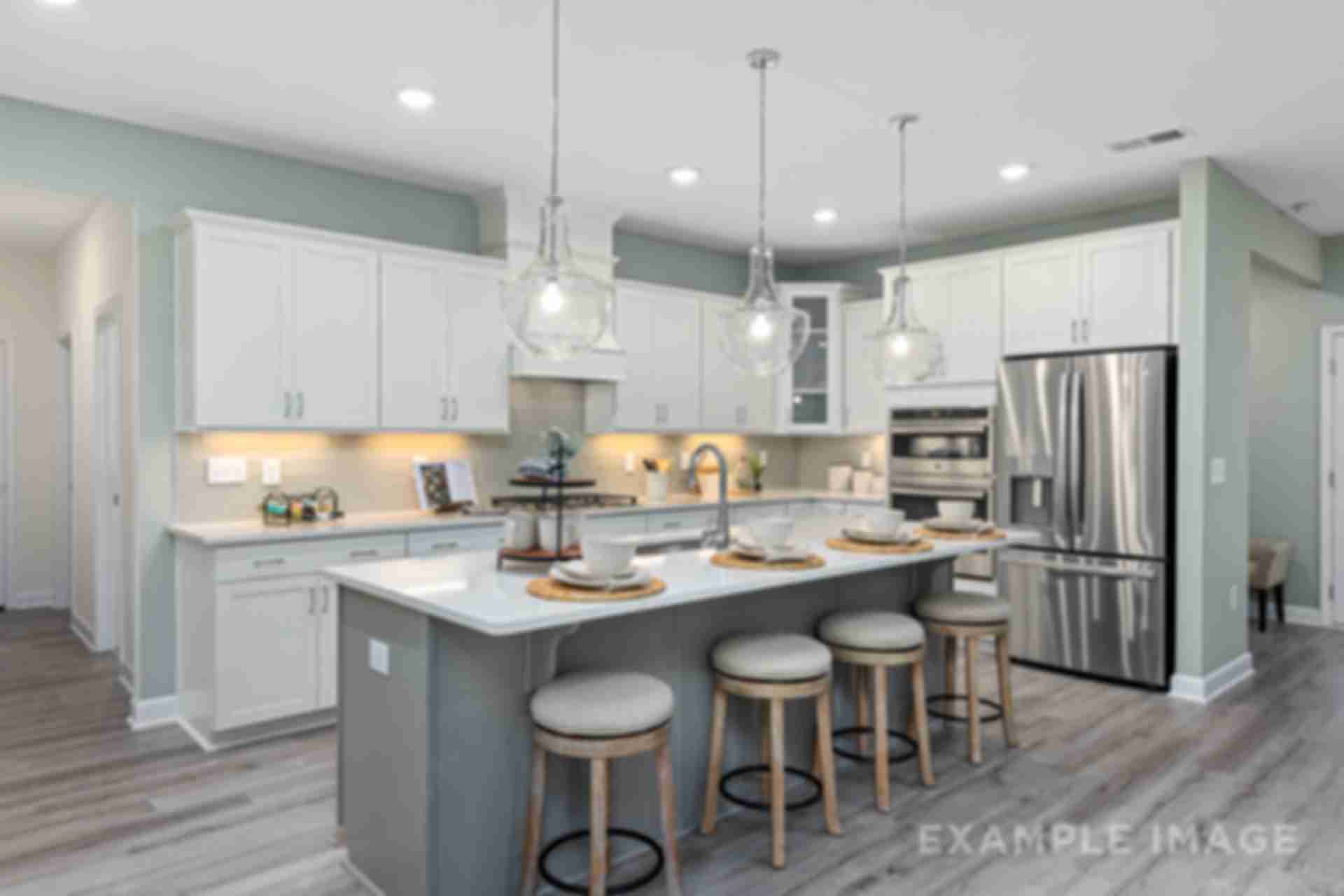 Modern open-concept kitchen in Windgate, Mooresville NC with white shaker cabinets, gray island, bar stools, stainless steel appliances, and hardwood floors