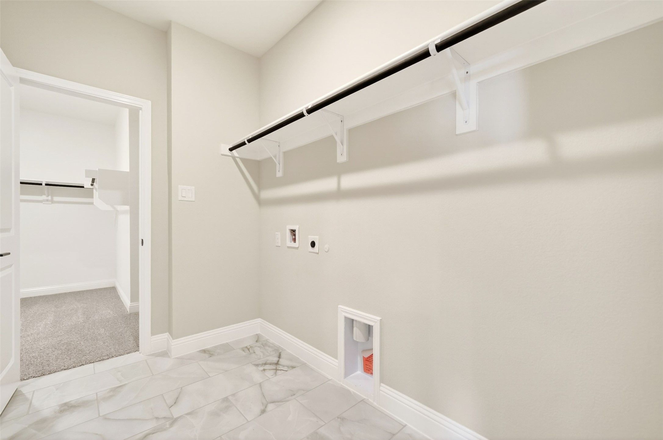Spacious laundry room with tile flooring and clothing rack in Davidson Homes The Holly C floor plan, Anna, Texas.