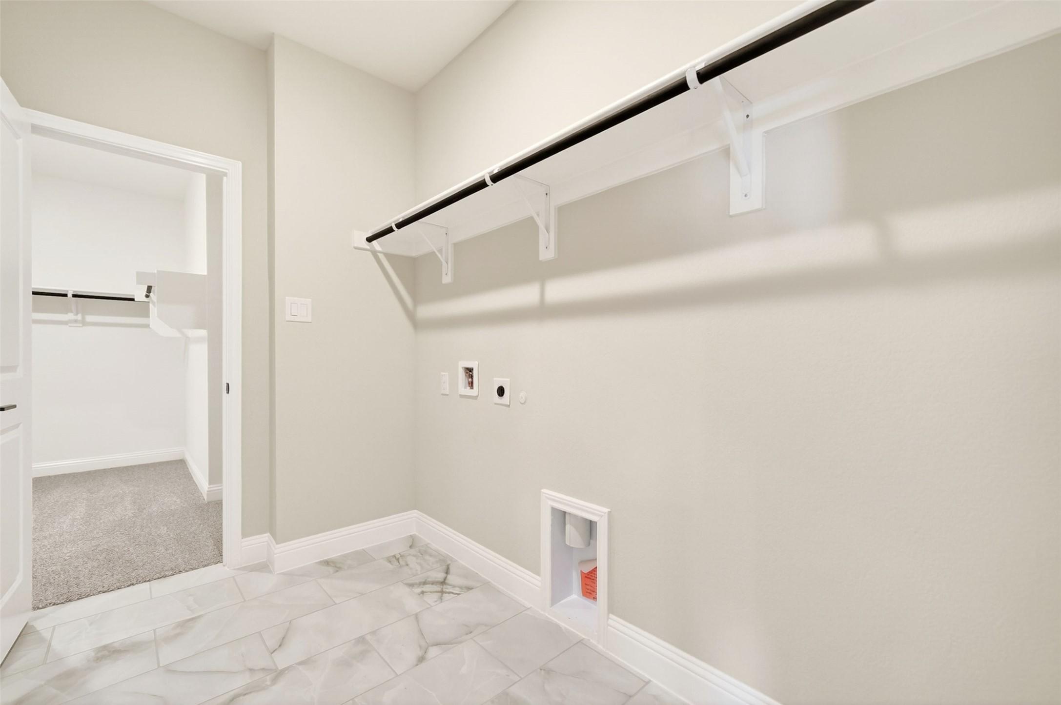 Spacious laundry room with tile flooring and clothing rack in Davidson Homes The Holly C floor plan, Anna, Texas.
