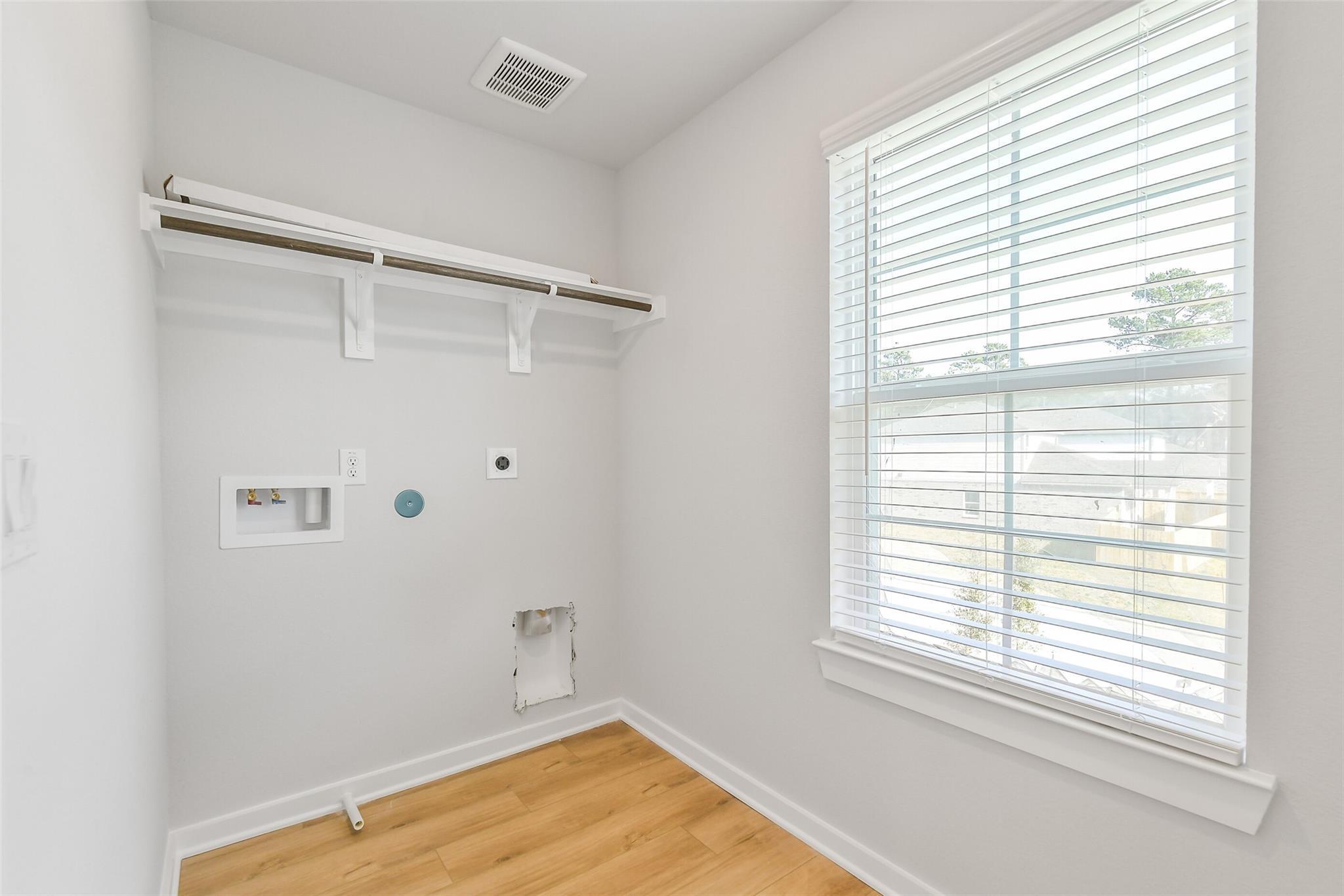 Bright laundry room with washer/dryer hookups, white shelves, and window blinds in Davidson Homes Trinity F, Magnolia TX