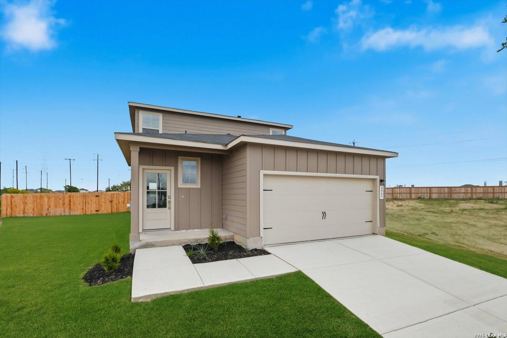 Two-story beige Sabine A home with 2-car garage, concrete driveway, and landscaped green lawn in Agave, San Antonio, Texas