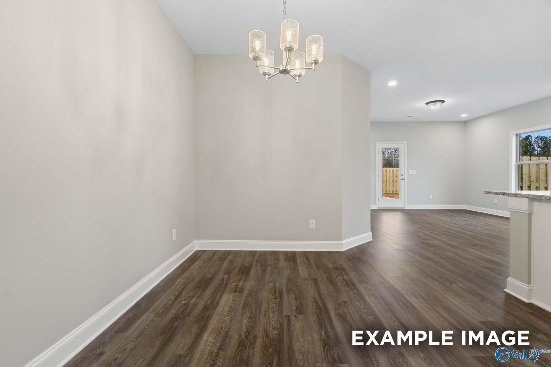 Elegant dining area with modern chandelier, hardwood floors, open to kitchen in The Camilla A 2-bedroom home, Hartselle, Alabama