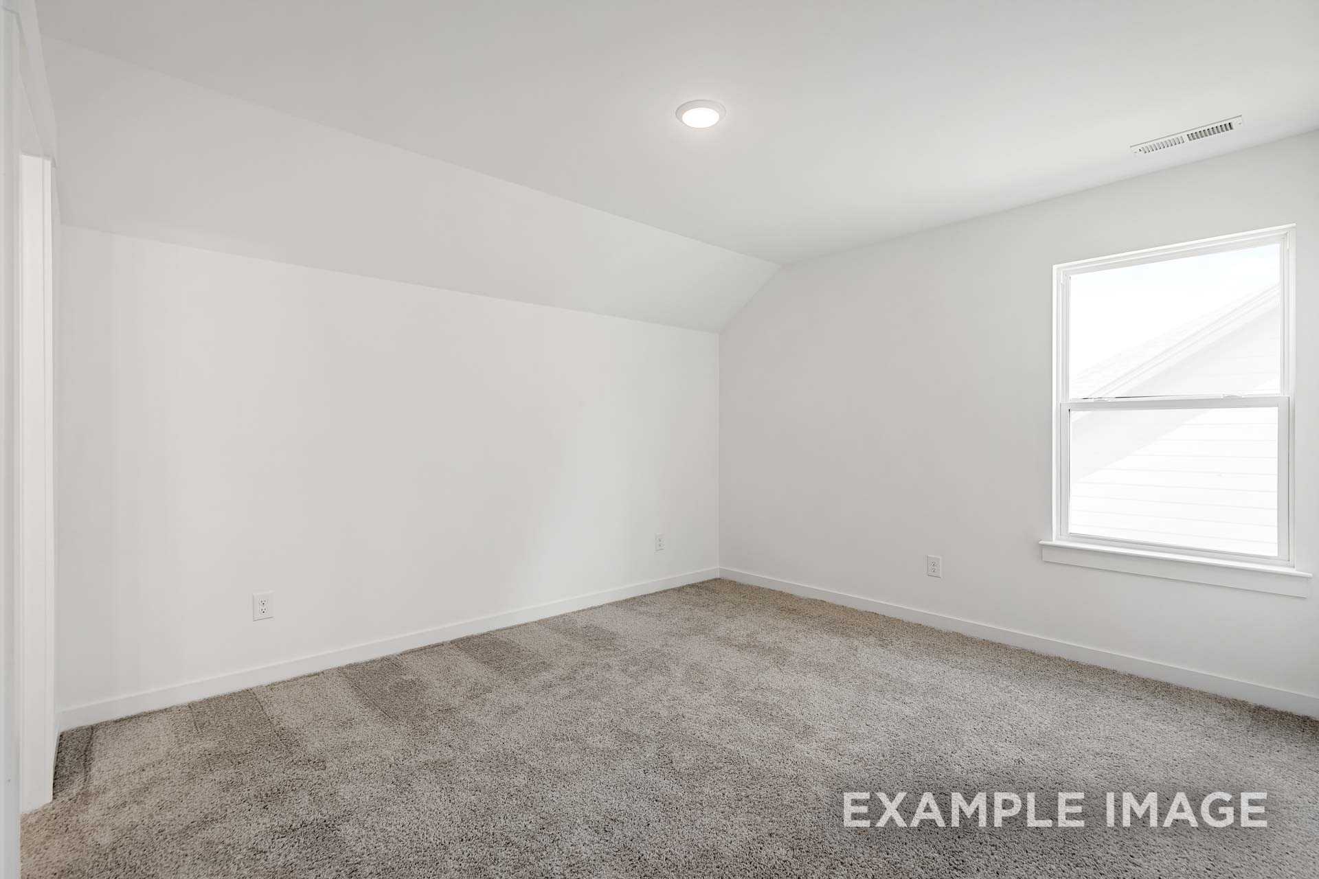 Spacious secondary bedroom in The Ash C with vaulted ceiling, white walls, beige carpet, and large window for natural light