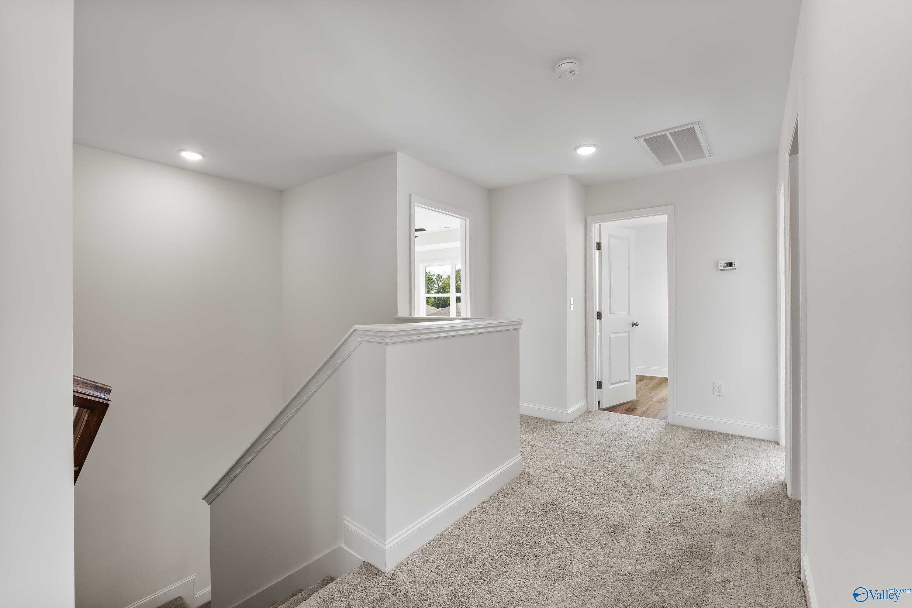 Bright upstairs hallway with carpeted floors, white walls, and bedroom doors in Davidson Homes The Shelby A, New Market, Alabama
