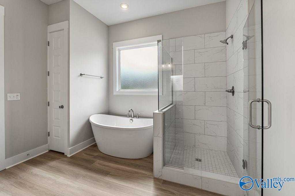 Luxurious master bathroom with freestanding tub, glass shower, and subway tiles in Evermore Homes The Oxford, Owens Cross Roads, AL
