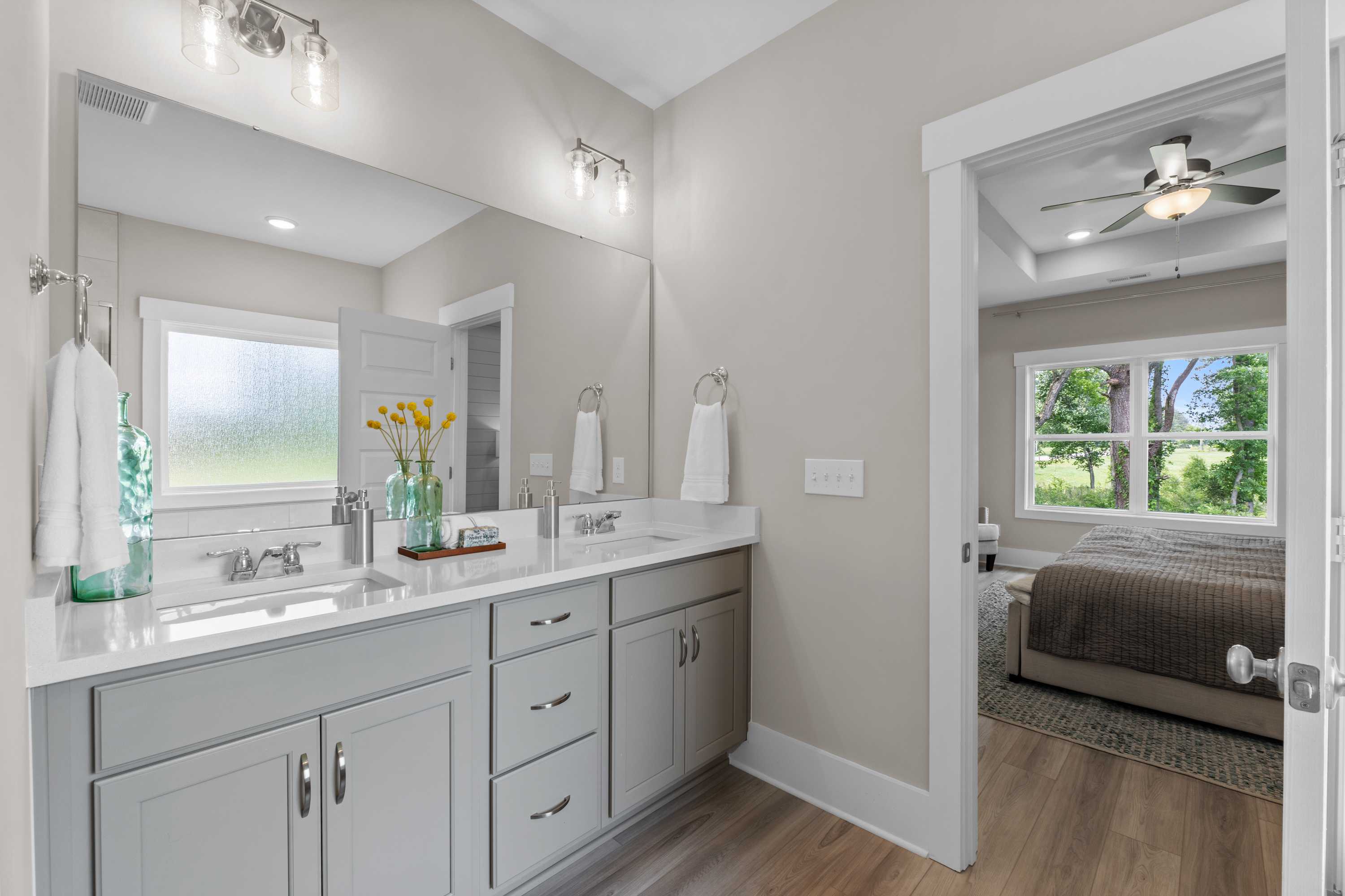 Spacious master bathroom at The Highlands in Arab Alabama with double vanity, gray cabinets, frosted window and bedroom view