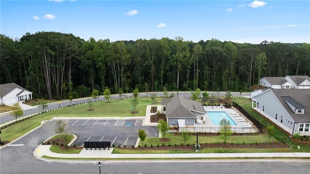 Aerial view of Kelly Preserve community with resort-style pool, modern homes, parking areas, and lush forests in Loganville, Georgia
