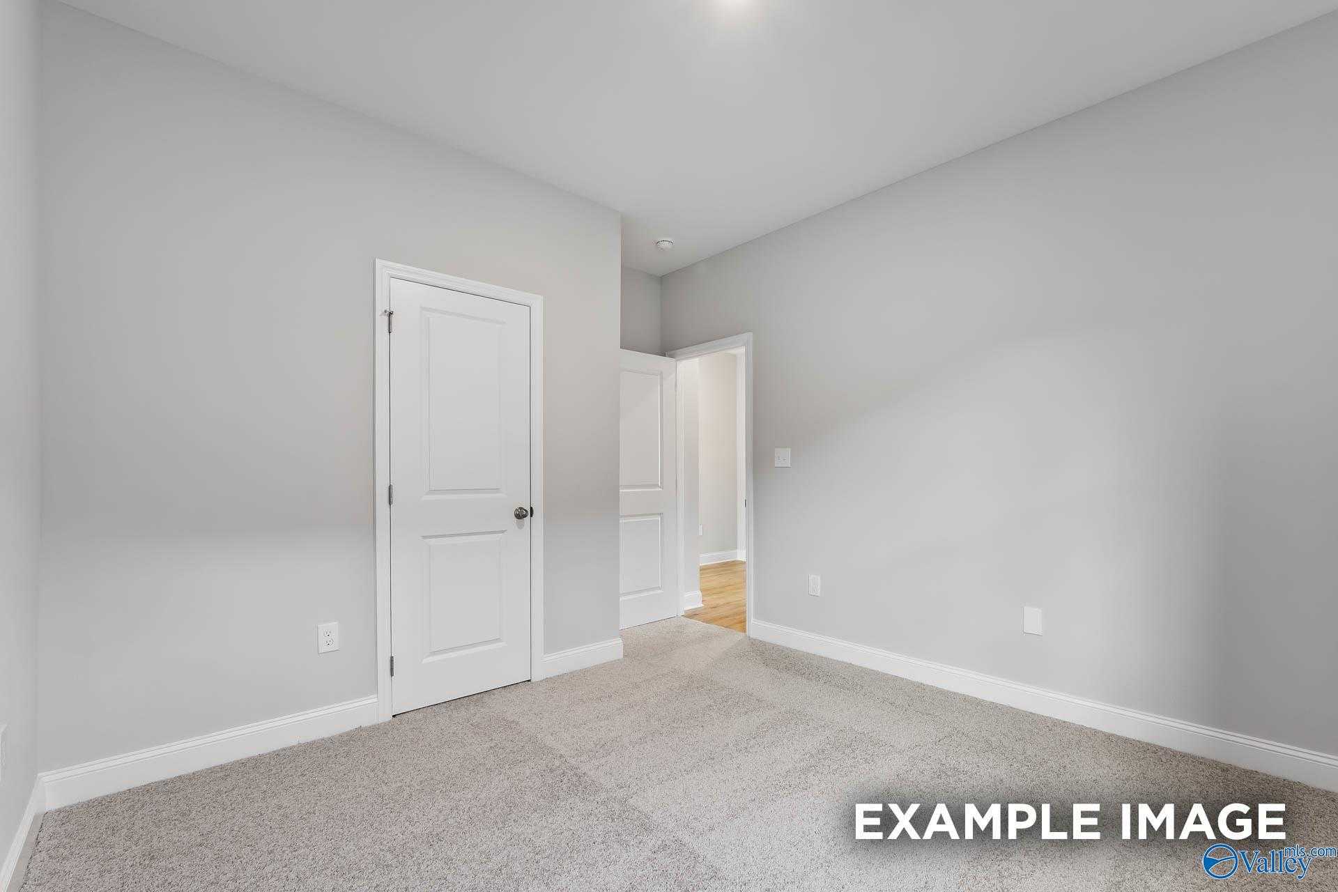 Spacious empty bedroom with gray walls, white doors, and carpet floor in Davidson Homes The Franklin C, Athens, Alabama