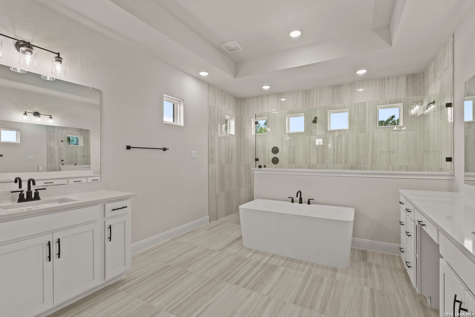 Modern primary bathroom with freestanding tub, glass-enclosed shower, and dual vanities in Davidson Homes The Summerlin B.