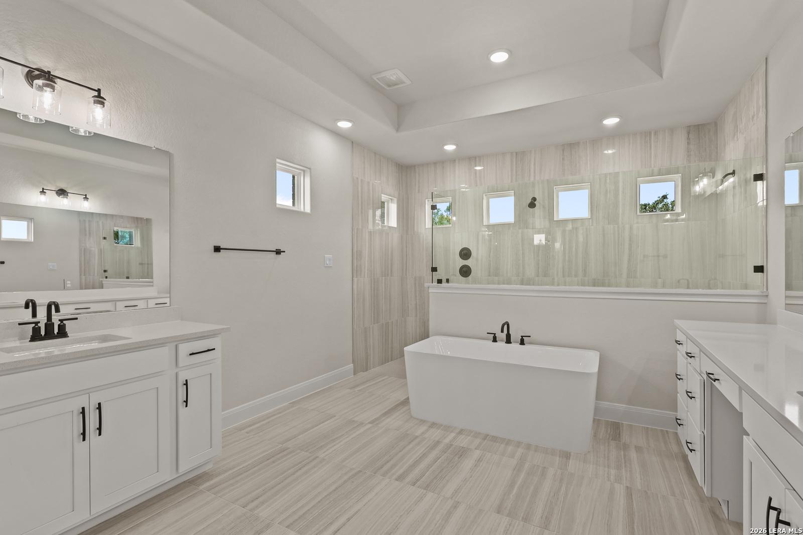 Modern primary bathroom with freestanding tub, glass-enclosed shower, and dual vanities in Davidson Homes The Summerlin B.