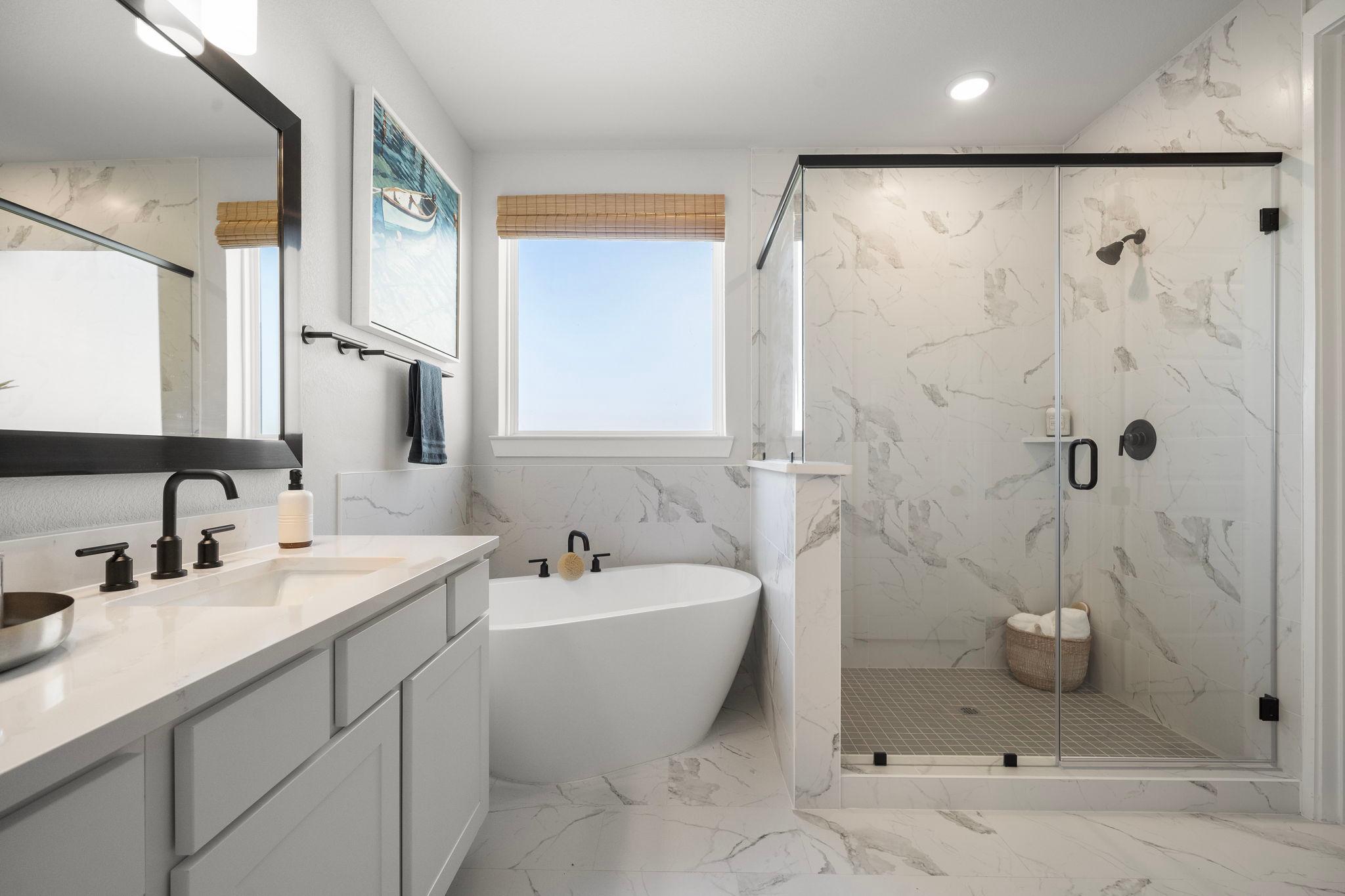 Luxurious primary bathroom at Lago Mar in Texas City Texas with freestanding tub glass shower and marble tiles