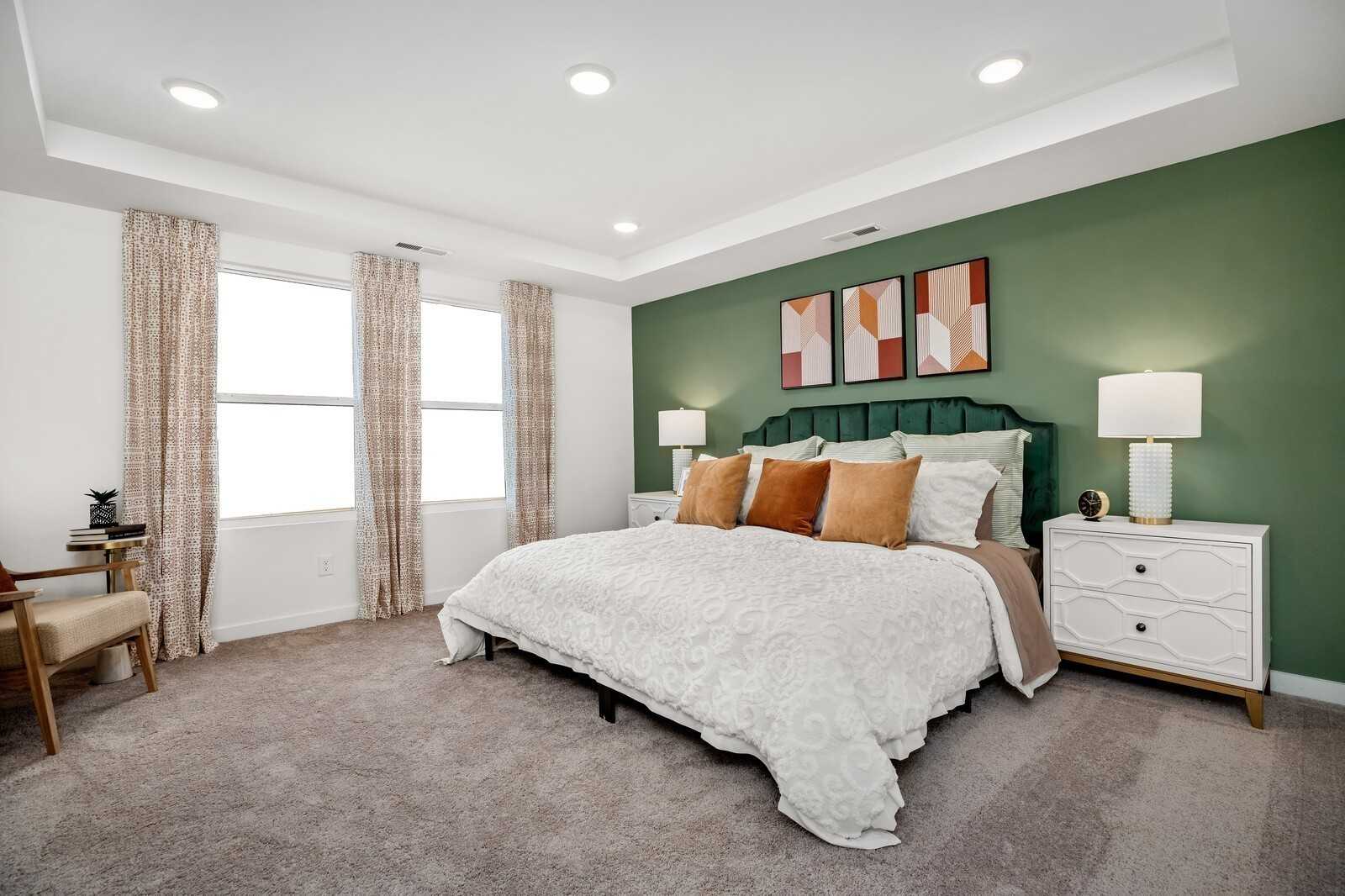 Elegant master bedroom with green accent wall, king bed, tufted headboard, and modern art in Davidson Homes The Gordon C, White House, TN