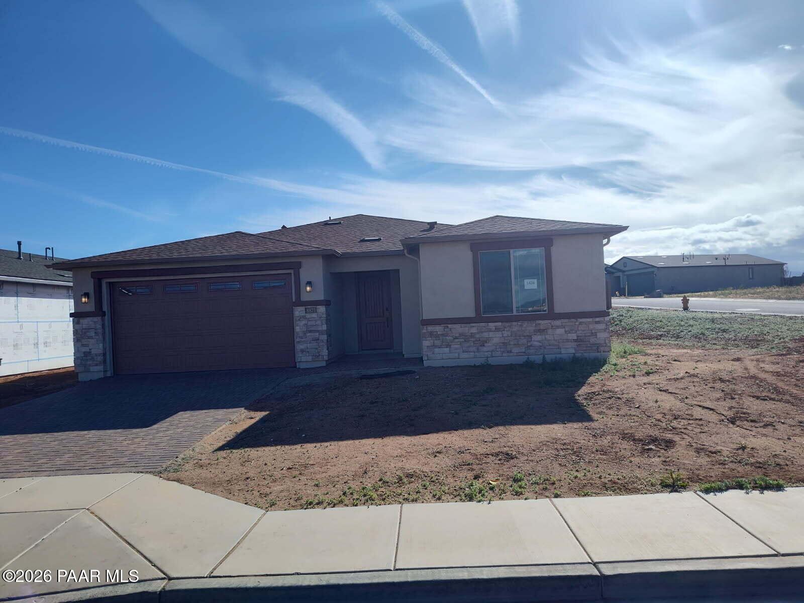 Modern single-story home with 3-car garage, stone accents, and paver driveway in North Ridge at Pronghorn Ranch, Prescott Valley, Arizona