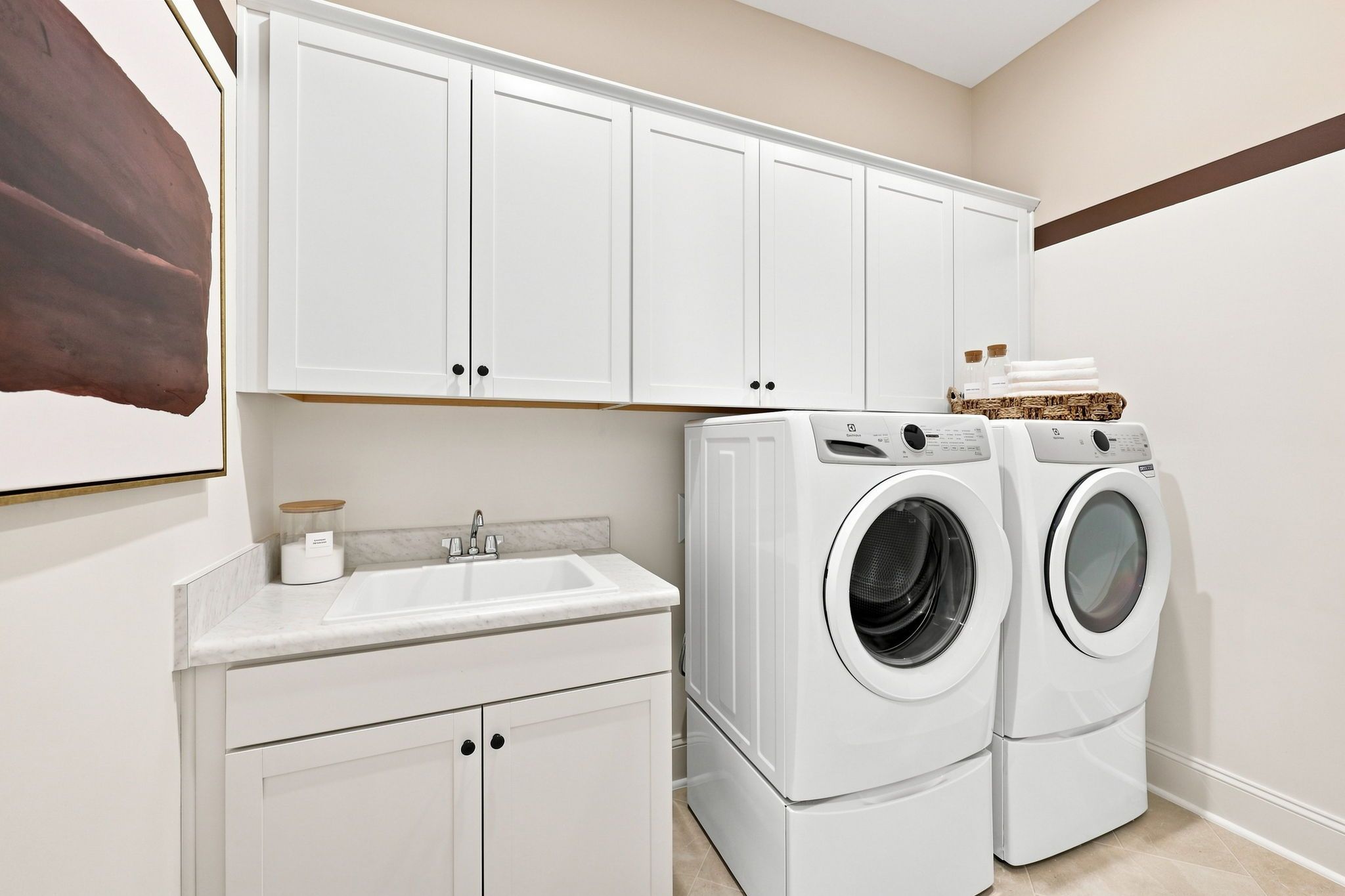 Laundry room in The Barrington C featuring white cabinetry, a utility sink, and modern washer and dryer appliances.