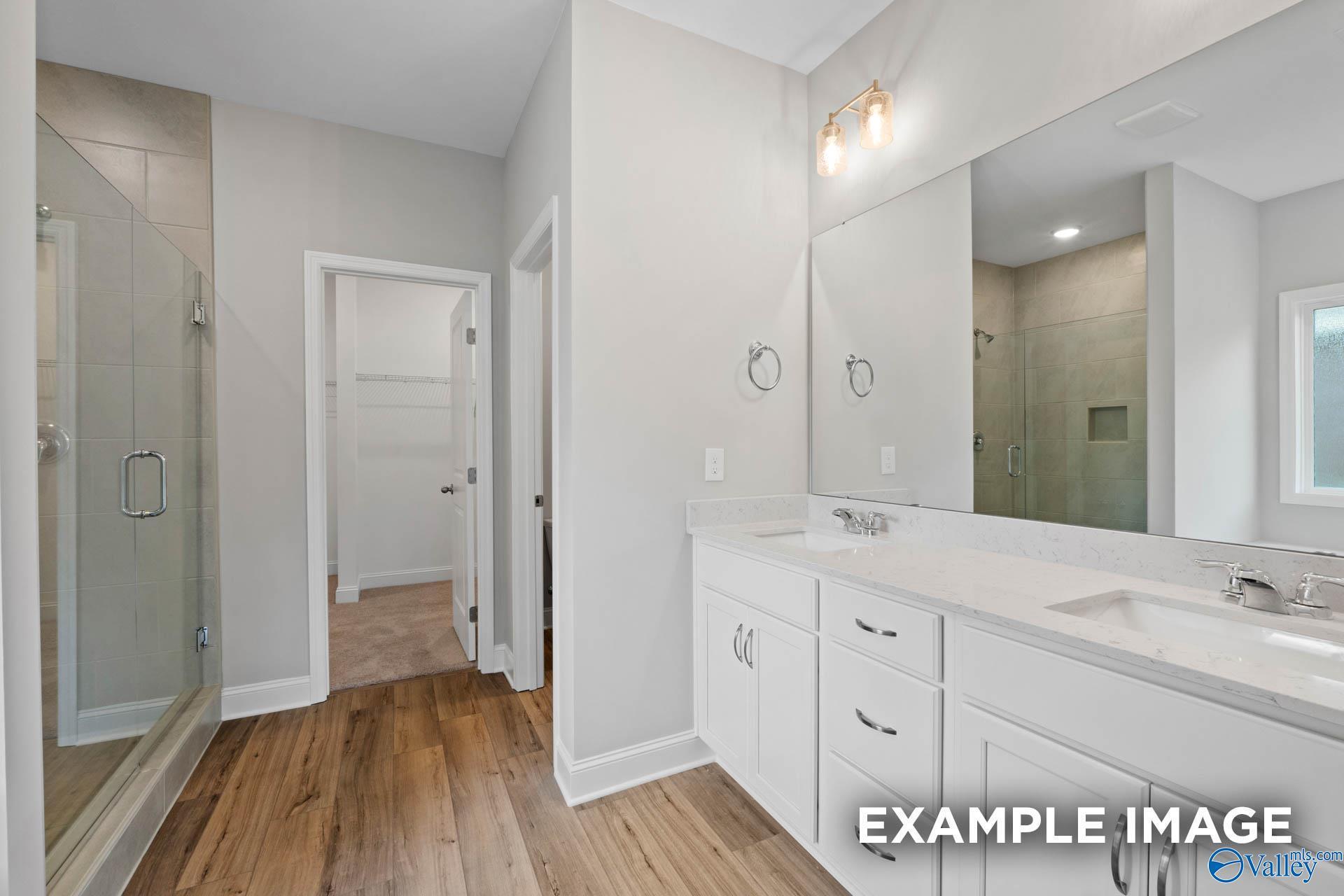 Modern master bathroom with frameless glass shower and double white vanity in Davidson Homes The Everett, Meridianville, AL