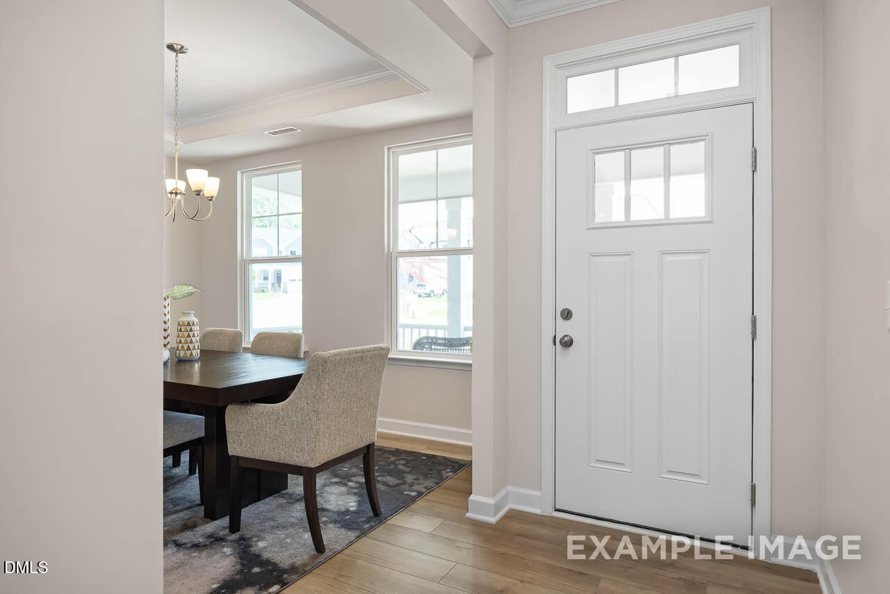 Elegant dining room with dark wood table, upholstered chairs, chandelier, and large windows in Davidson Homes The Willow D, Lillington, NC