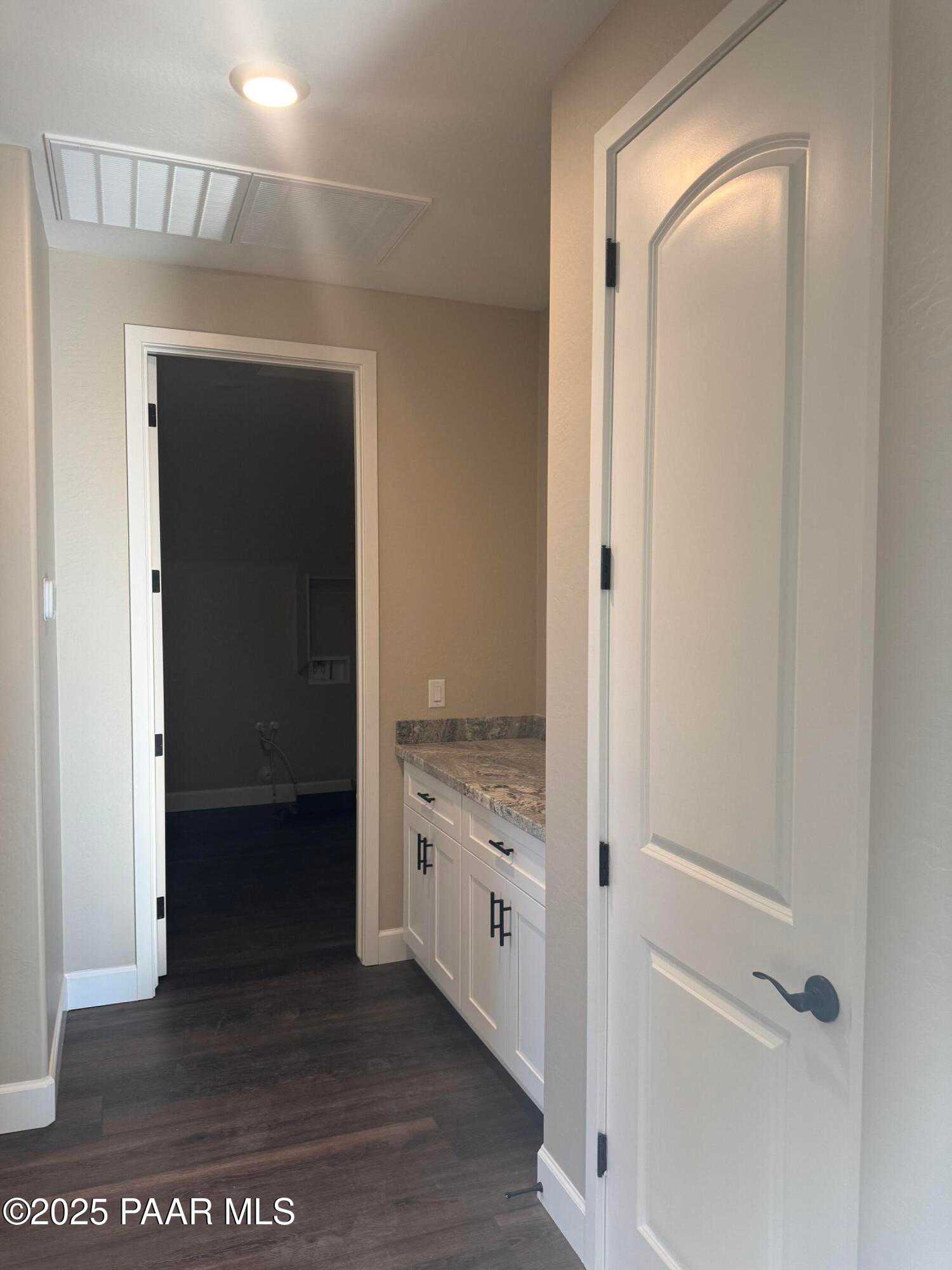Modern laundry room with white shaker cabinets, quartz countertop, and utility sink in Evermore Homes Sunrise A, Prescott Valley, AZ