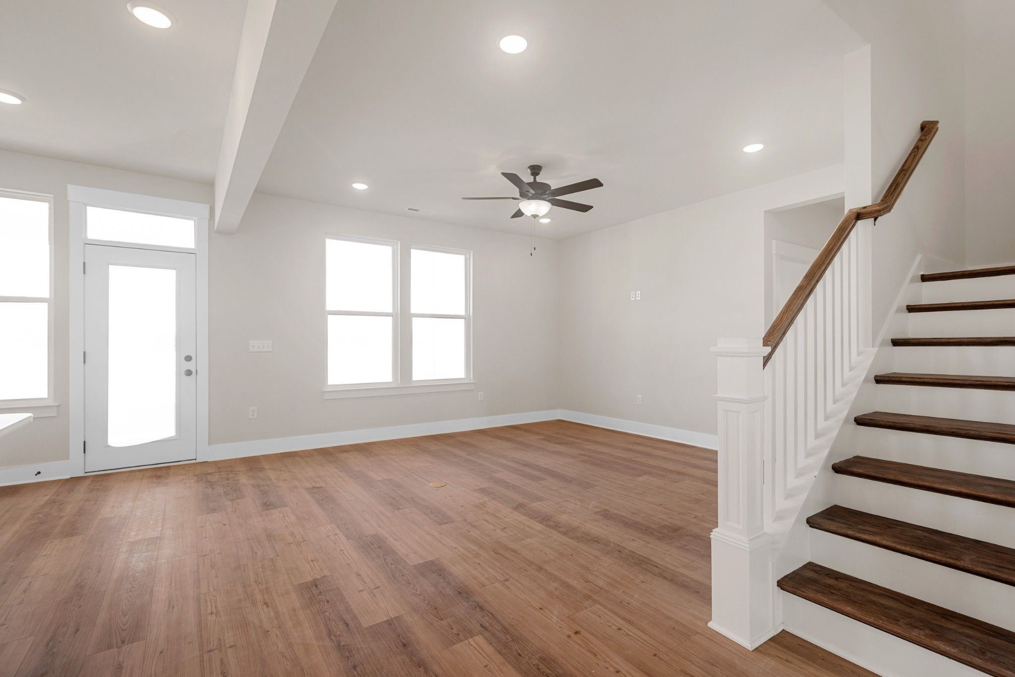 Bright foyer with hardwood floors, grand white staircase, ceiling fan, and large windows in Davidson Homes The Willow B, White House TN