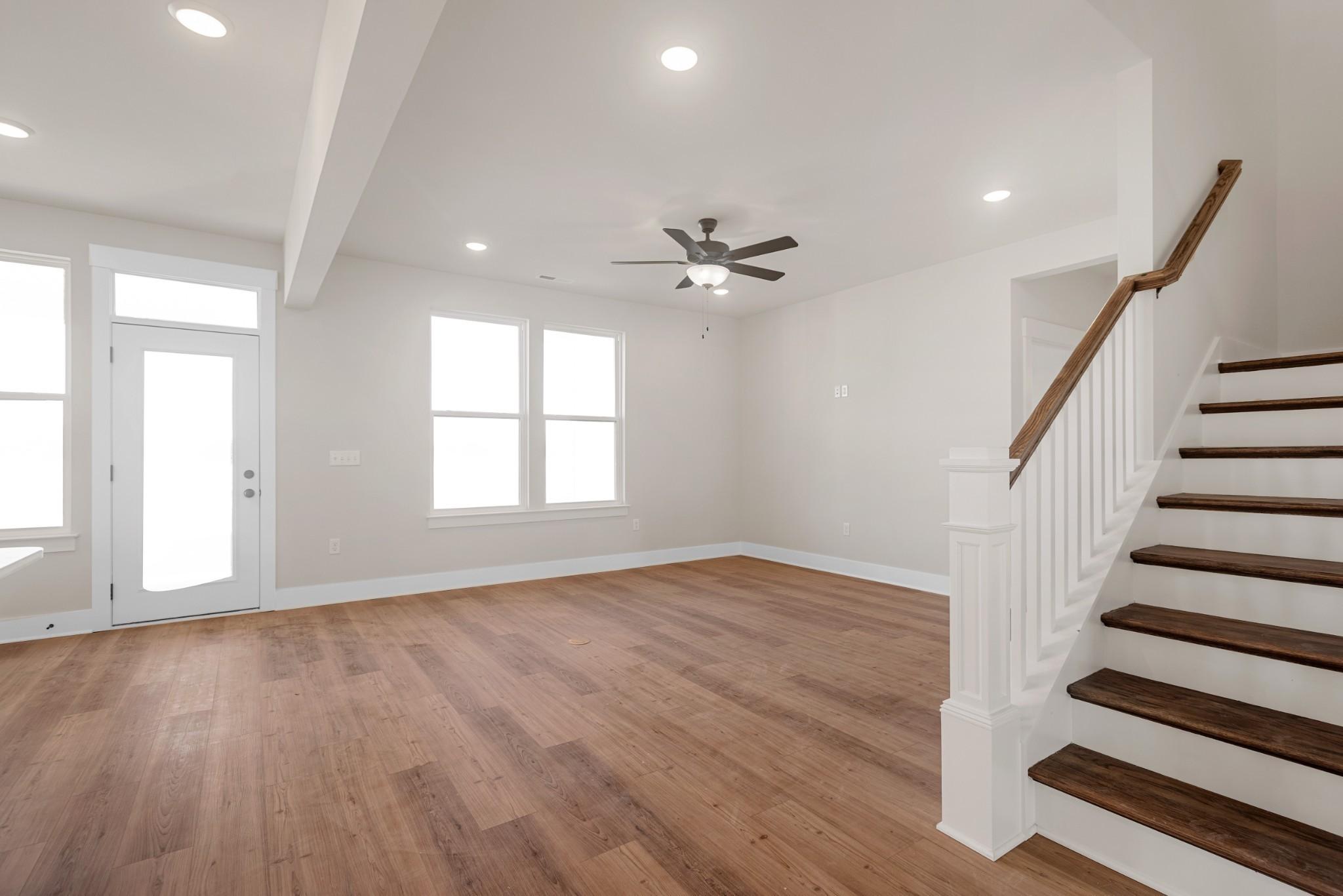 Bright foyer with hardwood floors, grand white staircase, ceiling fan, and large windows in Davidson Homes The Willow B, White House TN