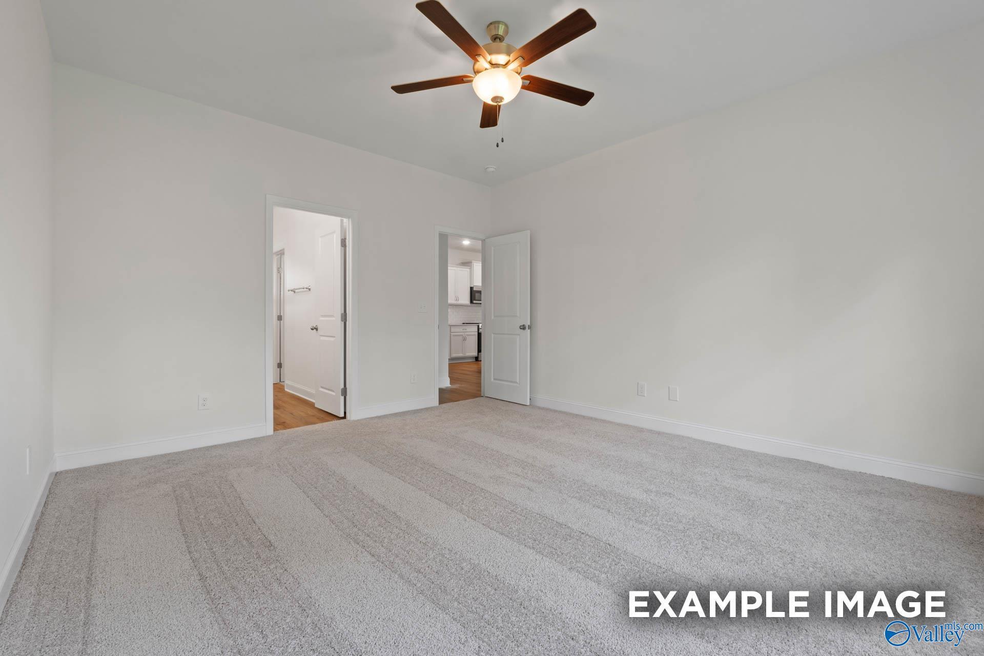 Spacious carpeted bedroom with ceiling fan and adjacent bathroom in The Daphne E 4-bedroom home, Harvest, Alabama