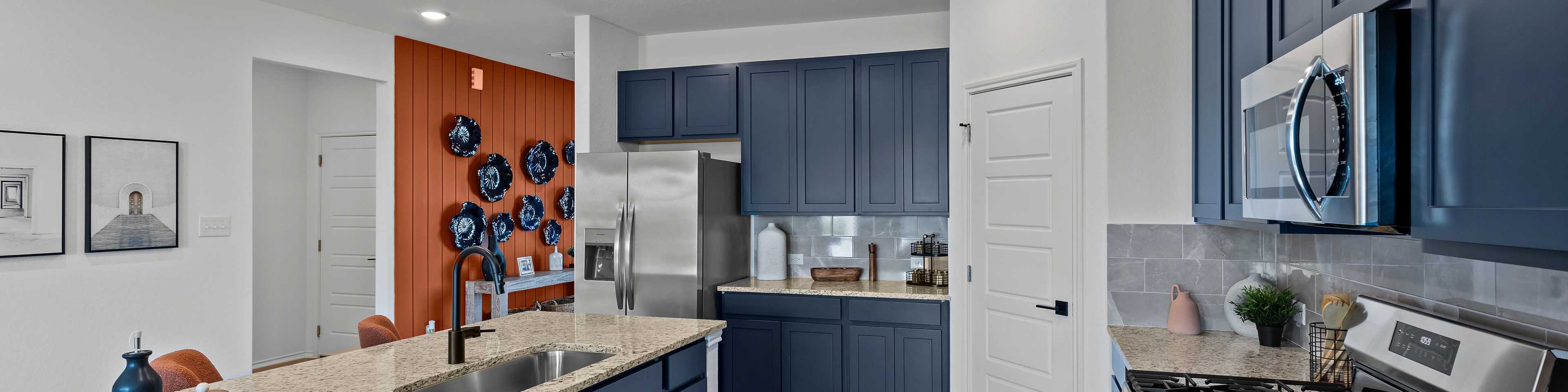 Spacious modern kitchen at Hickory Ridge in Elmendorf TX featuring navy cabinets, quartz counters, stainless appliances, and wood floors