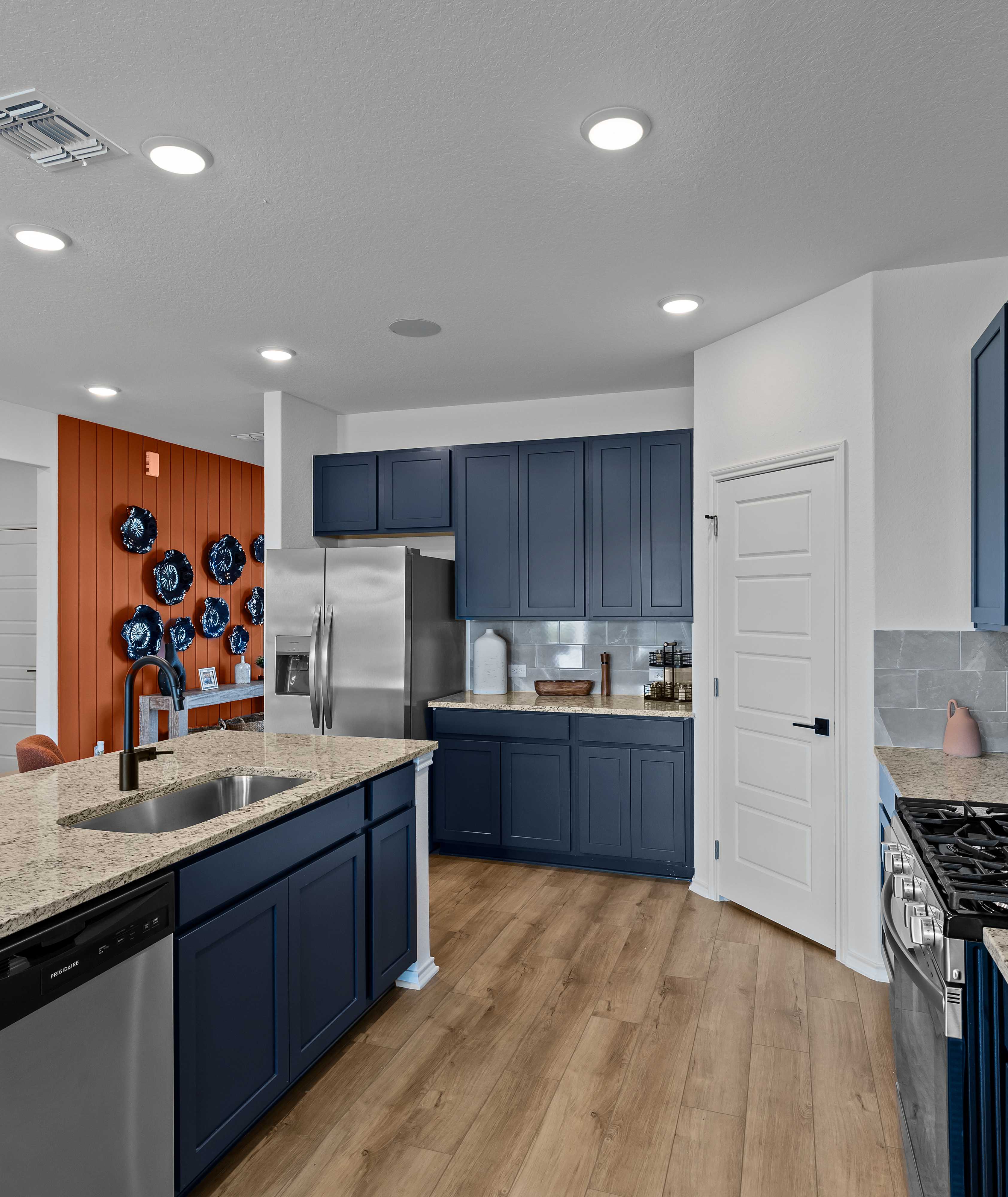 Spacious modern kitchen at Hickory Ridge in Elmendorf TX featuring navy cabinets, quartz counters, stainless appliances, and wood floors