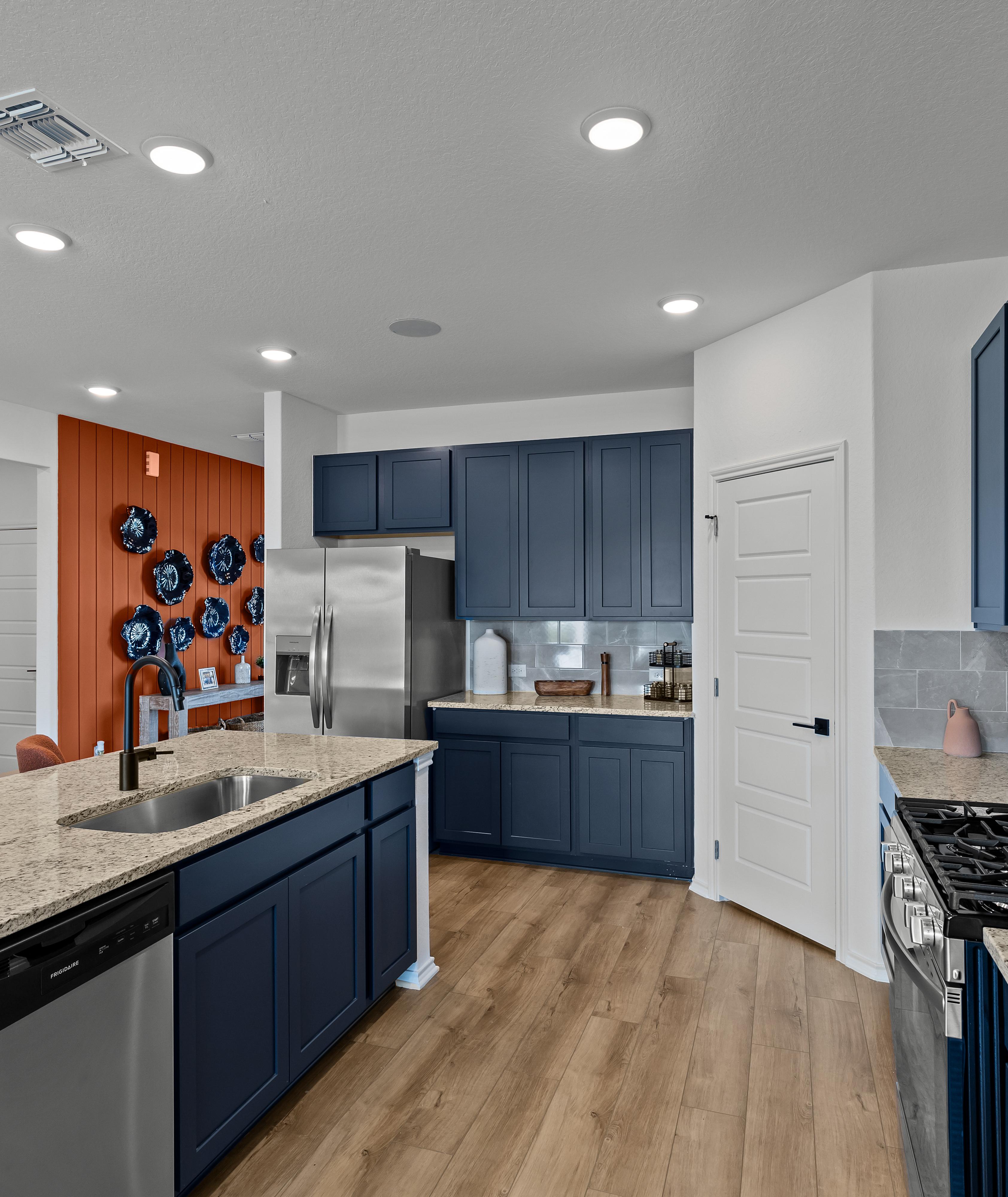 Spacious modern kitchen at Hickory Ridge in Elmendorf TX featuring navy cabinets, quartz counters, stainless appliances, and wood floors