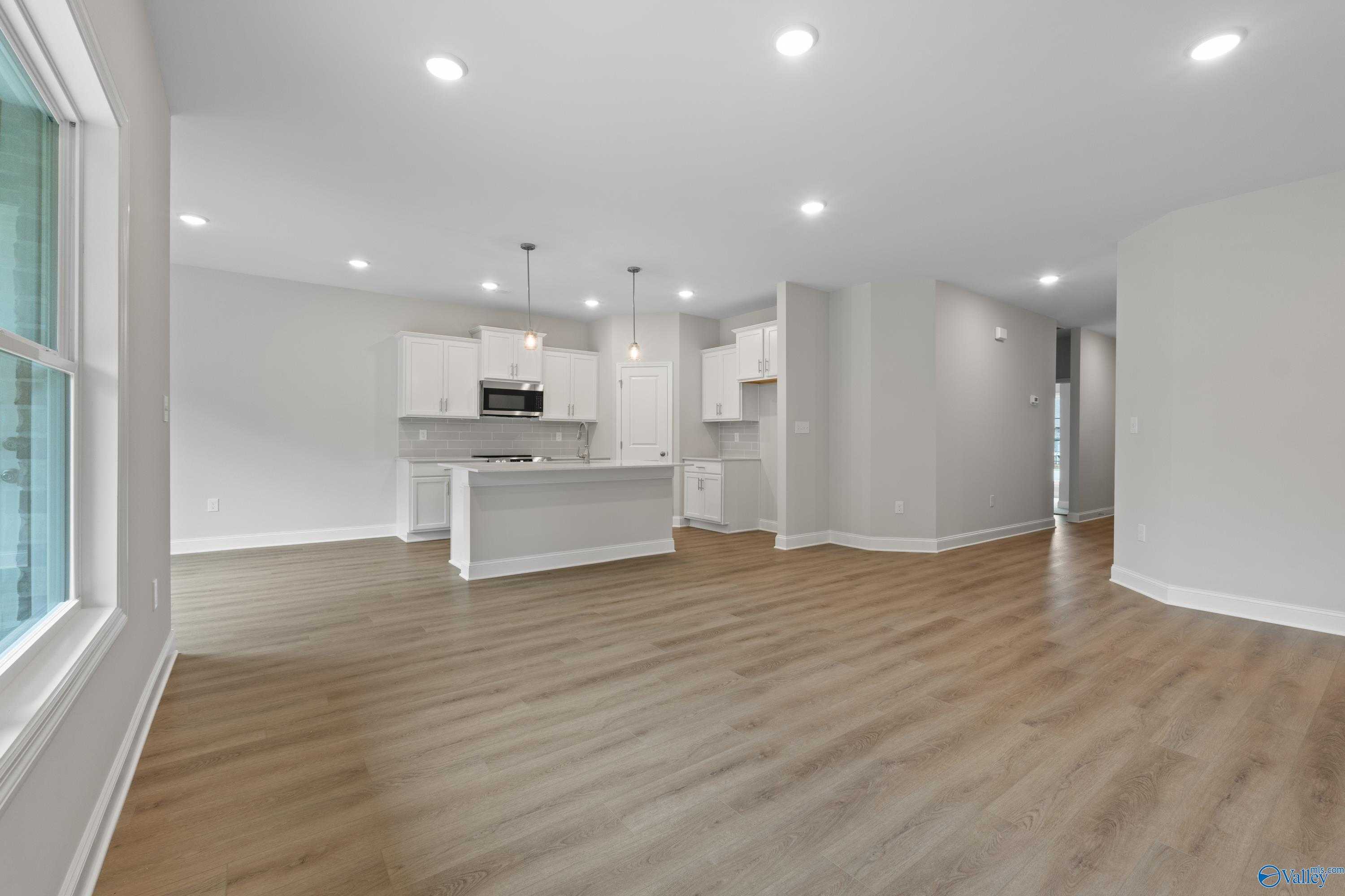 Modern open-concept kitchen with white shaker cabinets, stainless appliances, and island in The Asheville C, Davidson Homes, Huntsville AL