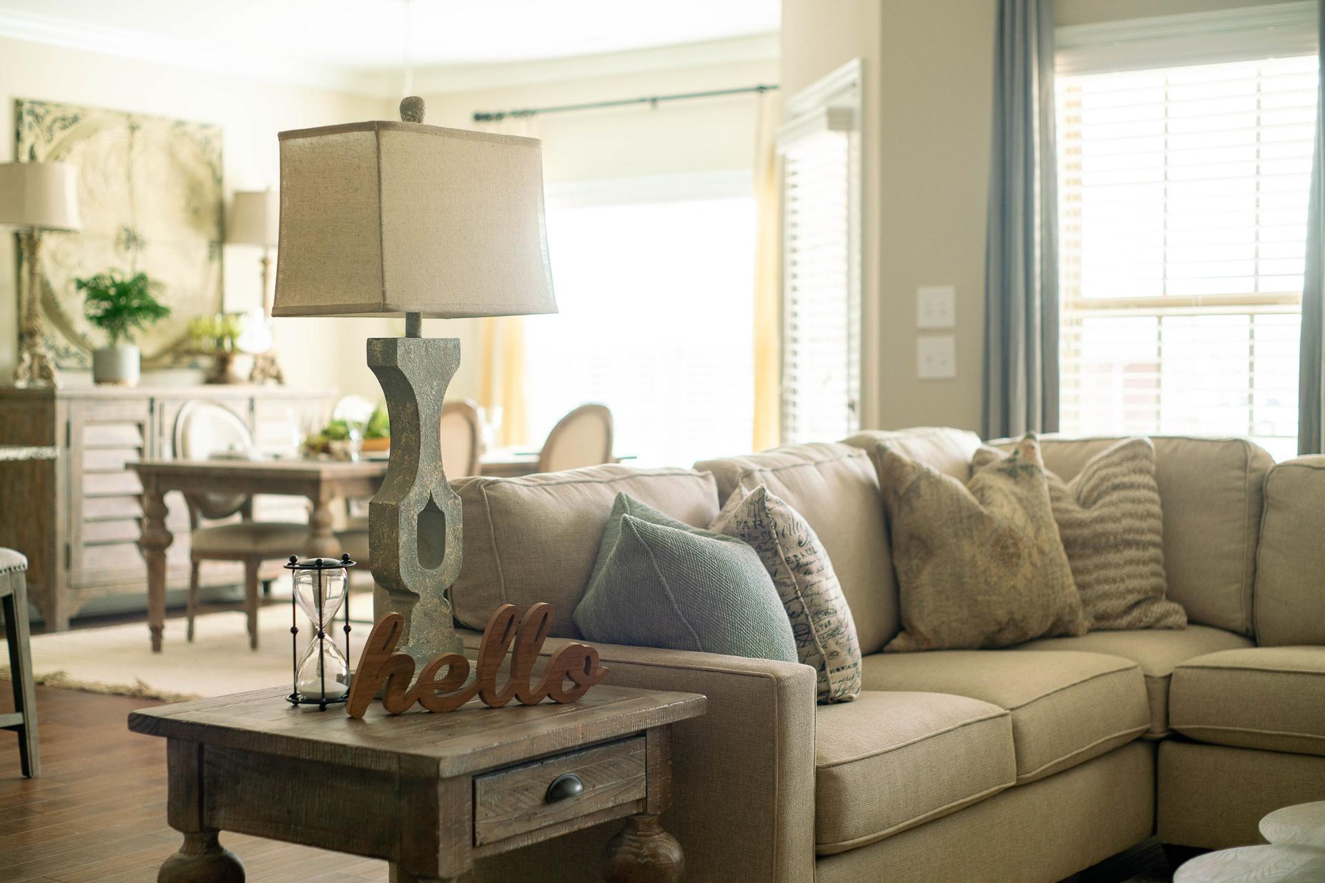 Cozy living room at The Dairy at Oak Grove in South Huntsville AL with beige sectional sofa, tall lamp, and hardwood floors