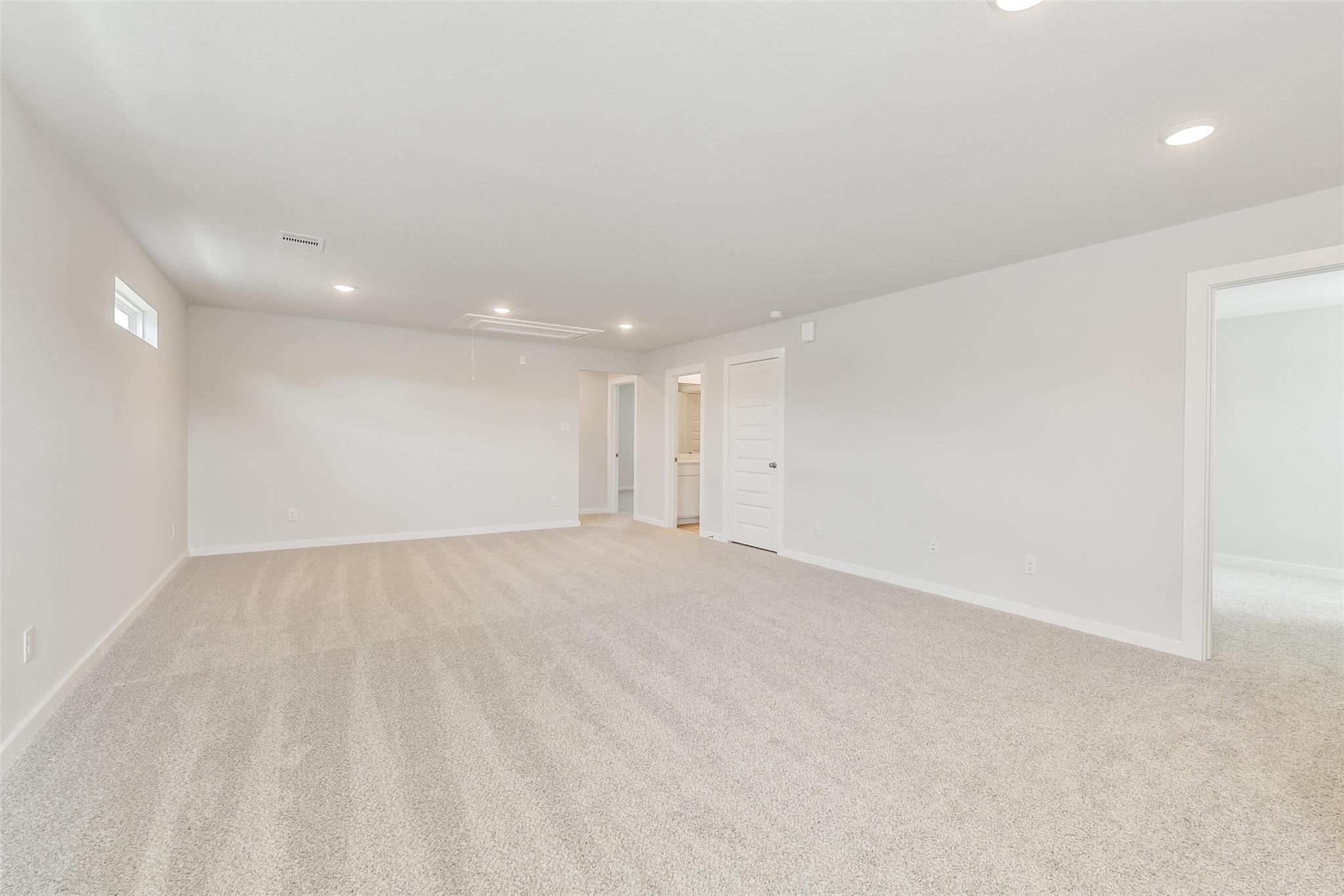 Spacious empty bonus room with beige carpet, white walls, recessed lights, and adjacent bath in The San Marcos E home, Conroe, Texas