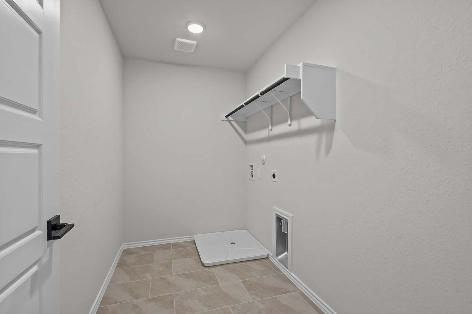 Spacious laundry room in The Florence B featuring tile flooring, washer-dryer hookups, and built-in shelving.