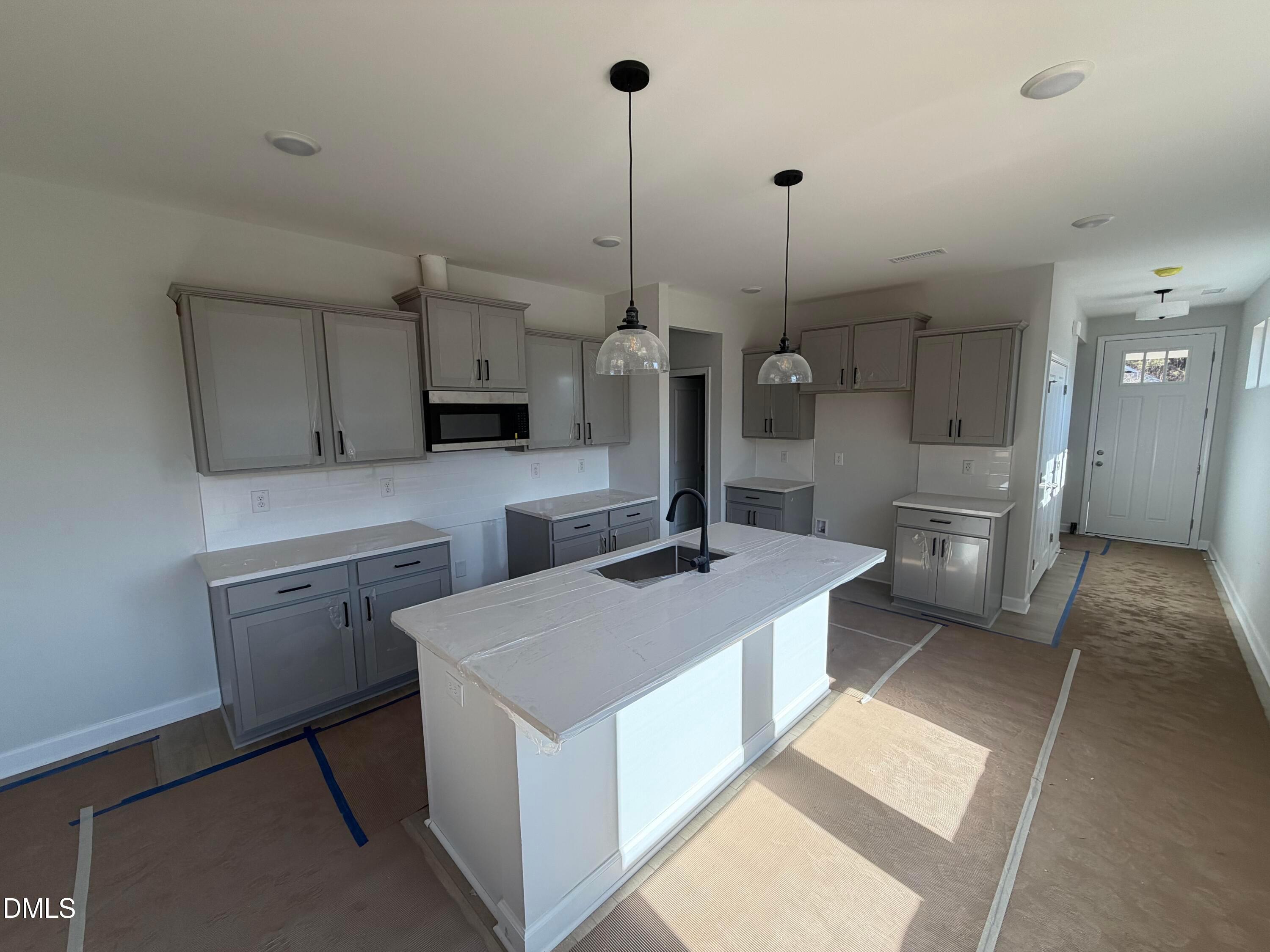 Modern gray kitchen with white quartz island, pendant lights, and stainless appliances in Davidson Homes The Carter C, Lillington NC