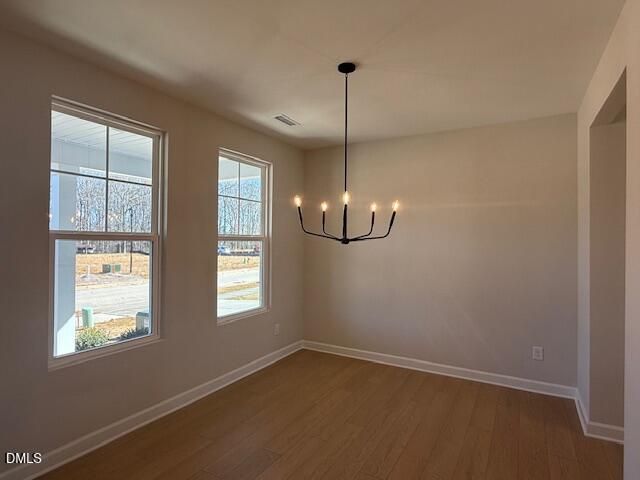 Sunlit dining room with large windows, modern black chandelier, hardwood floors in The Willow D, Zebulon NC