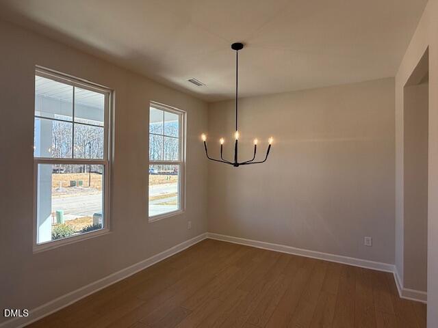 Sunlit dining room with large windows, modern black chandelier, hardwood floors in The Willow D, Zebulon NC