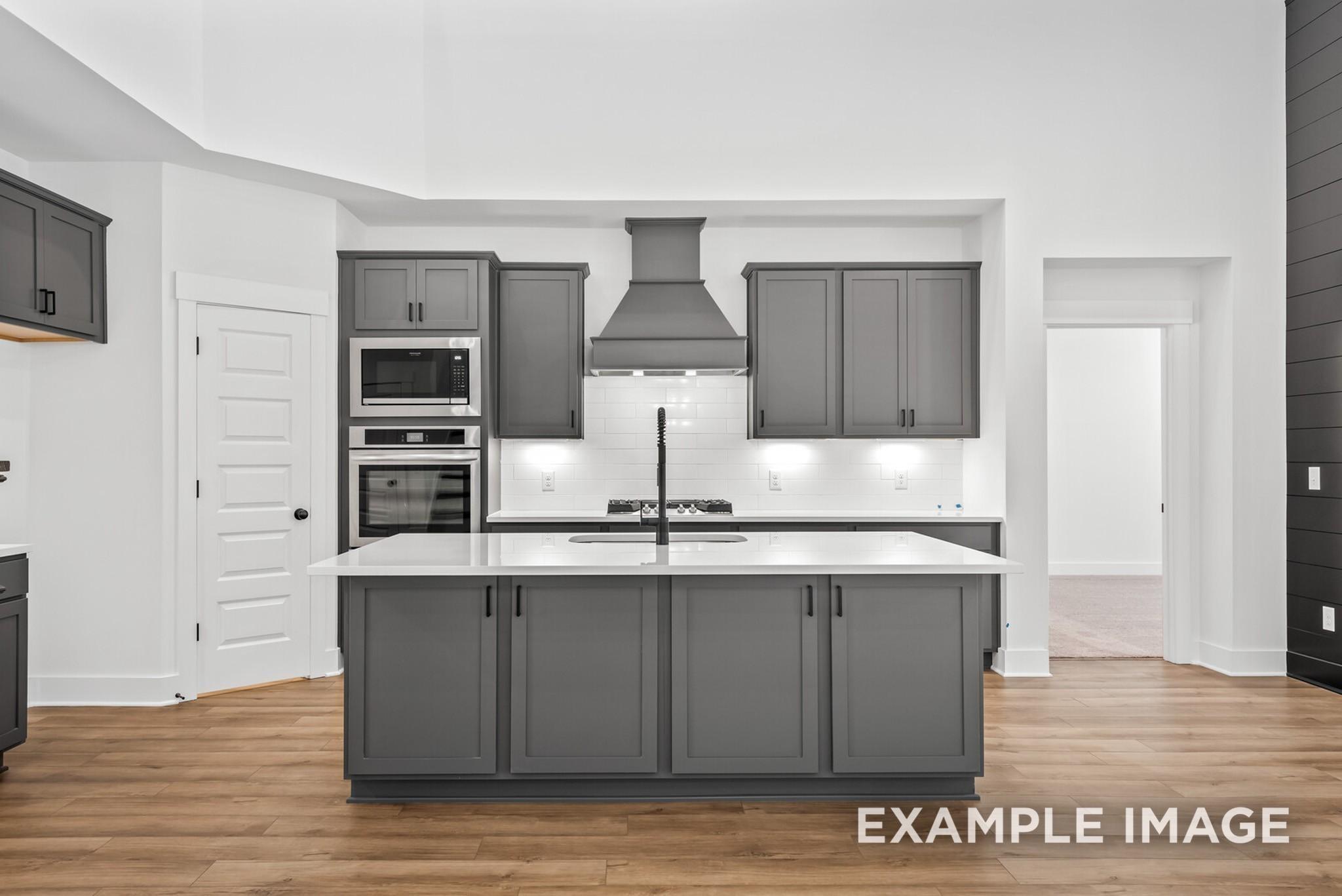 Modern open-concept kitchen featuring gray shaker cabinets, stainless steel appliances, and quartz island in Davidson Homes Ridgeport C, Gallatin, TN