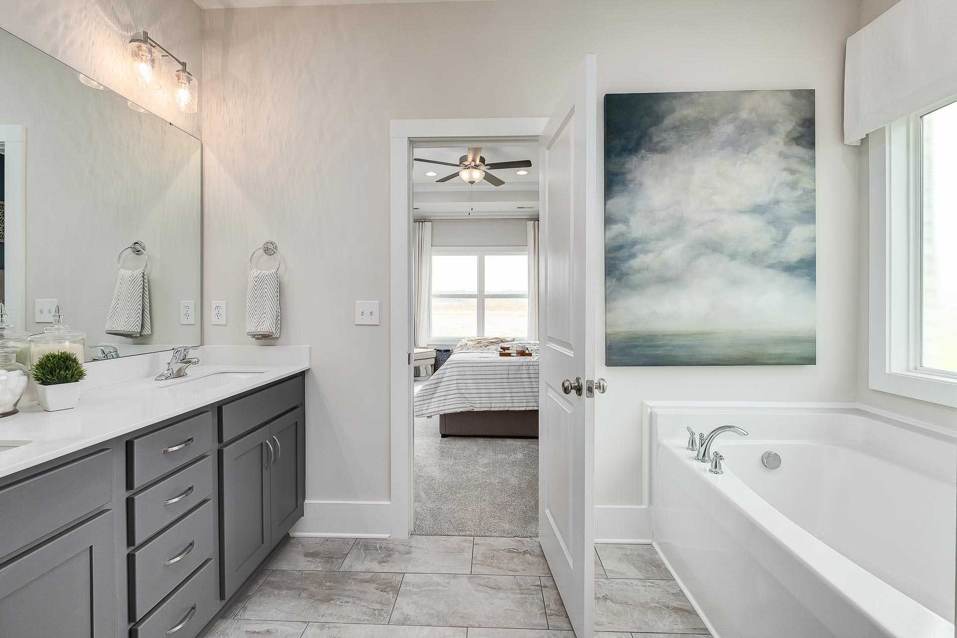 owner's bathroom with gray cabinets and soaking tub by Davidson Homes