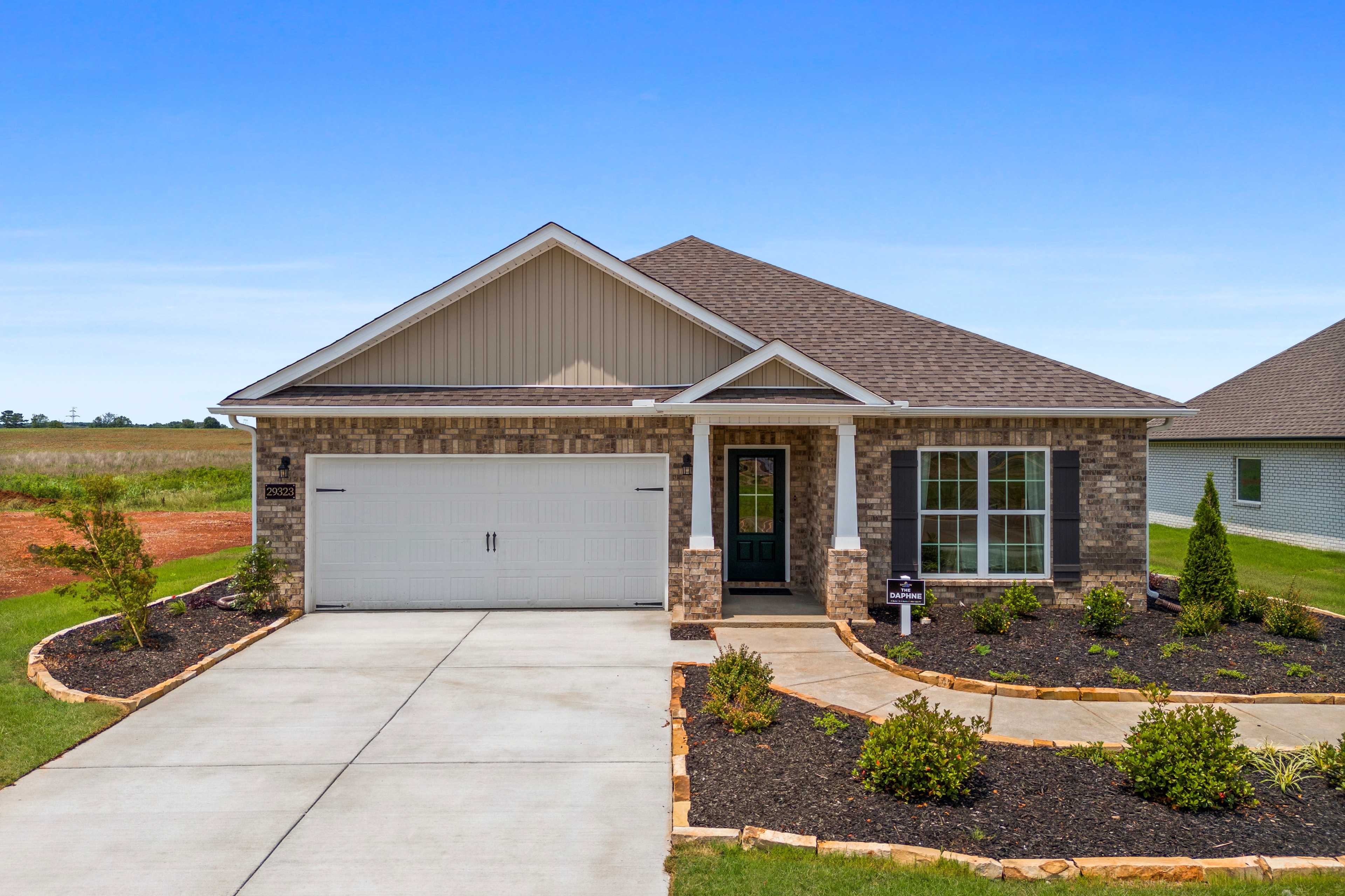 Contemporary ranch home exterior at Creekside in Harvest Alabama with brick accents, covered porch, attached garage, and landscaped driveway