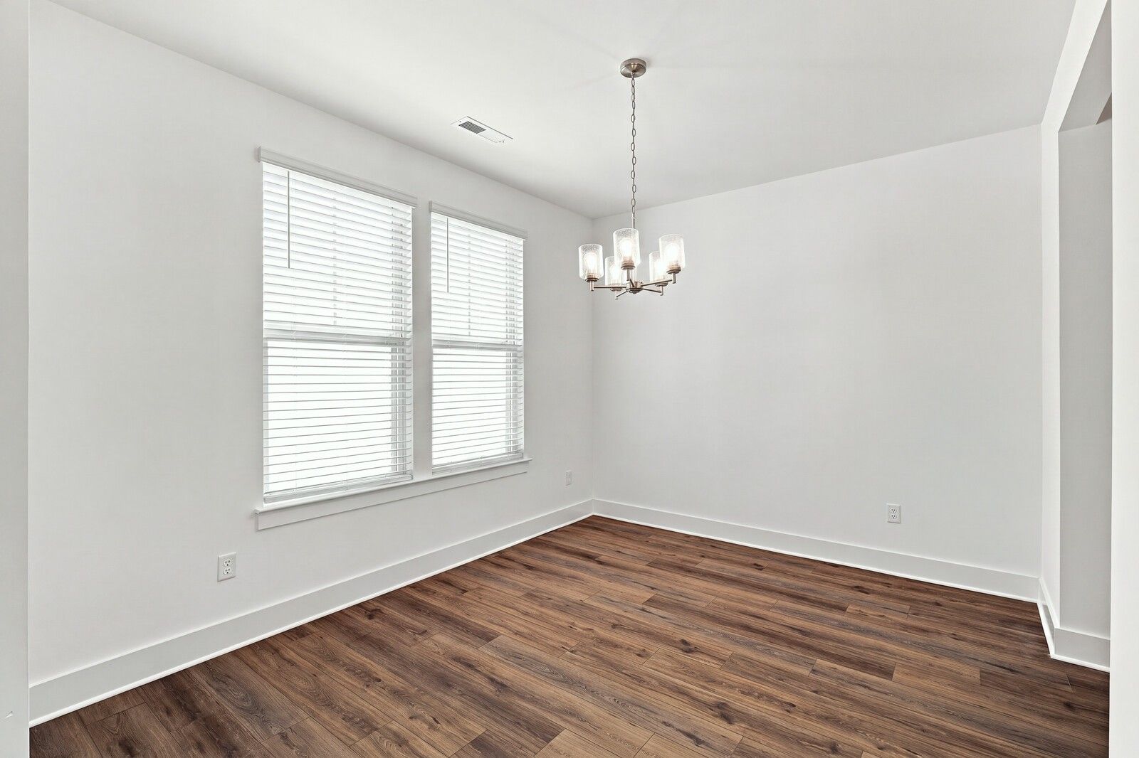 Bright dining room with wood-look flooring, white walls, and chandelier in The Willow C plan at Woods Crossing, Gallatin TN